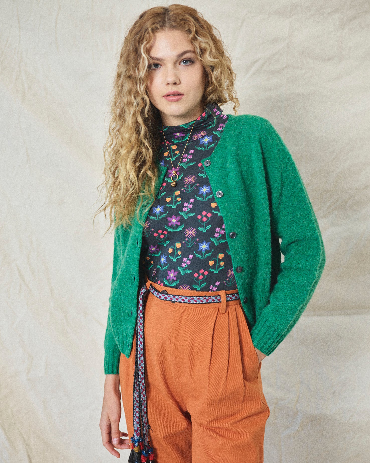 A pair of orange wide leg trousers with pleats and a fixed turn-up hem, made from cotton drill fabric.