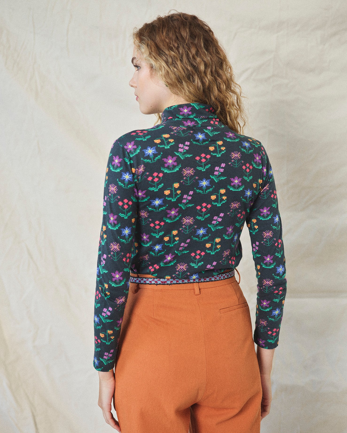 A long sleeve printed roll neck t-shirt with a turtle pattern in multicolor on a black background, made from organic cotton.