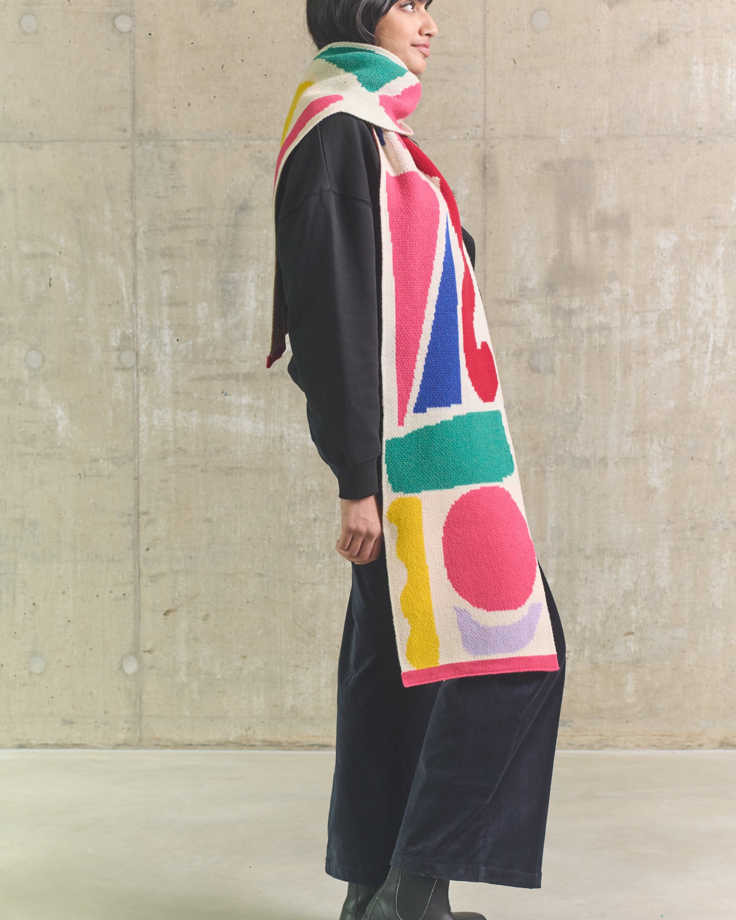 Person wearing a colorful scarf with abstract patterns against a plain background