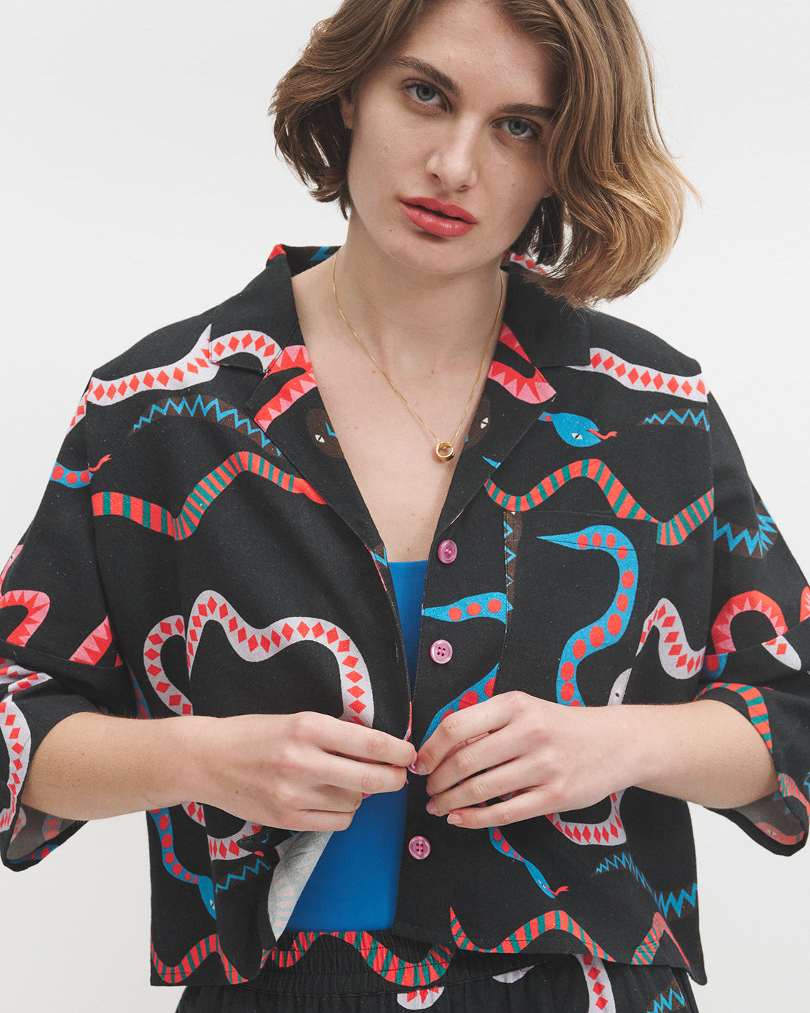 Woman wearing a black jacket with colorful snake patterns on a white background