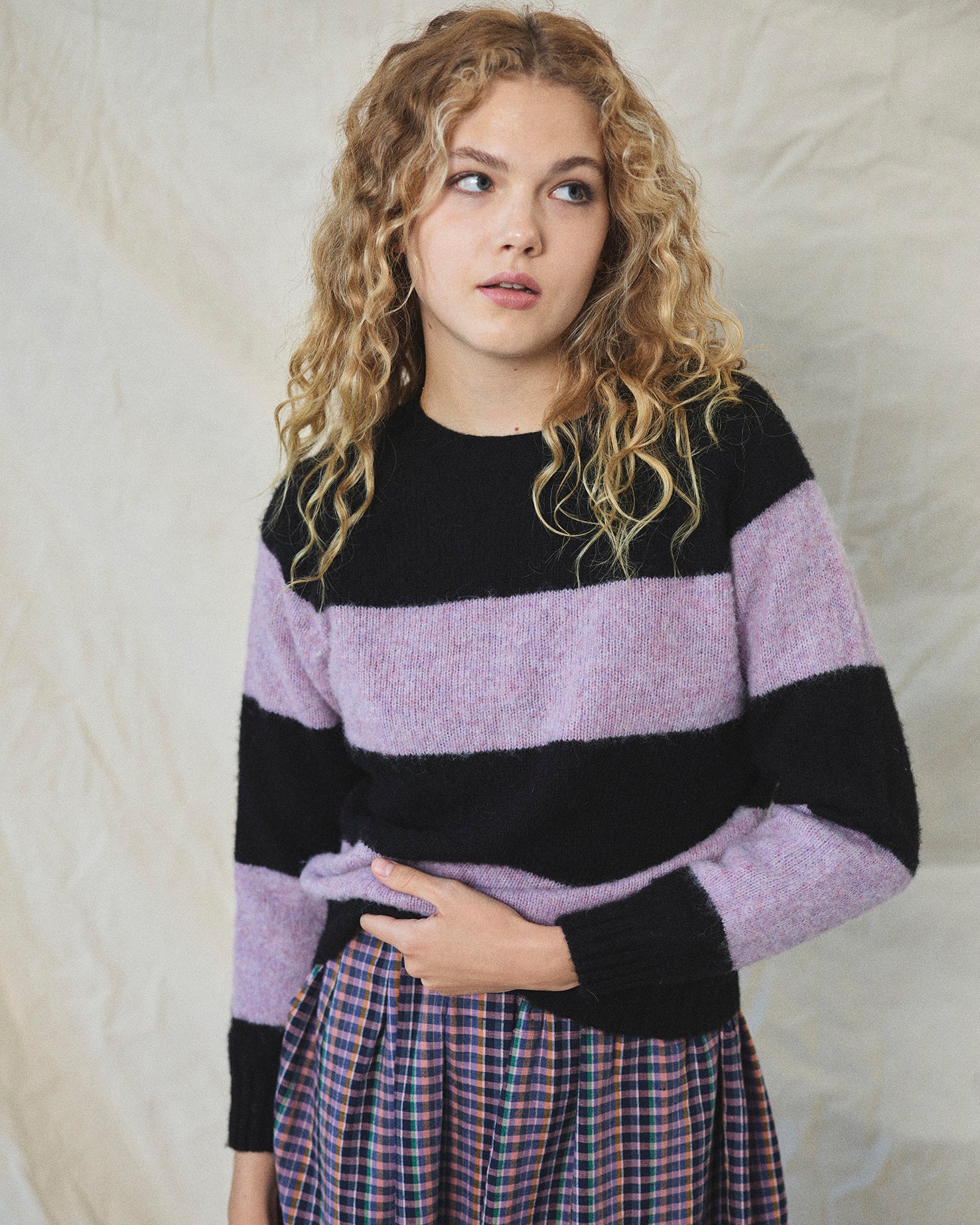 A striped Scottish jumper with horizontal black and lilac blocks, featuring a round neckline and ribbed-knit hemline and trim around neck and wrist.