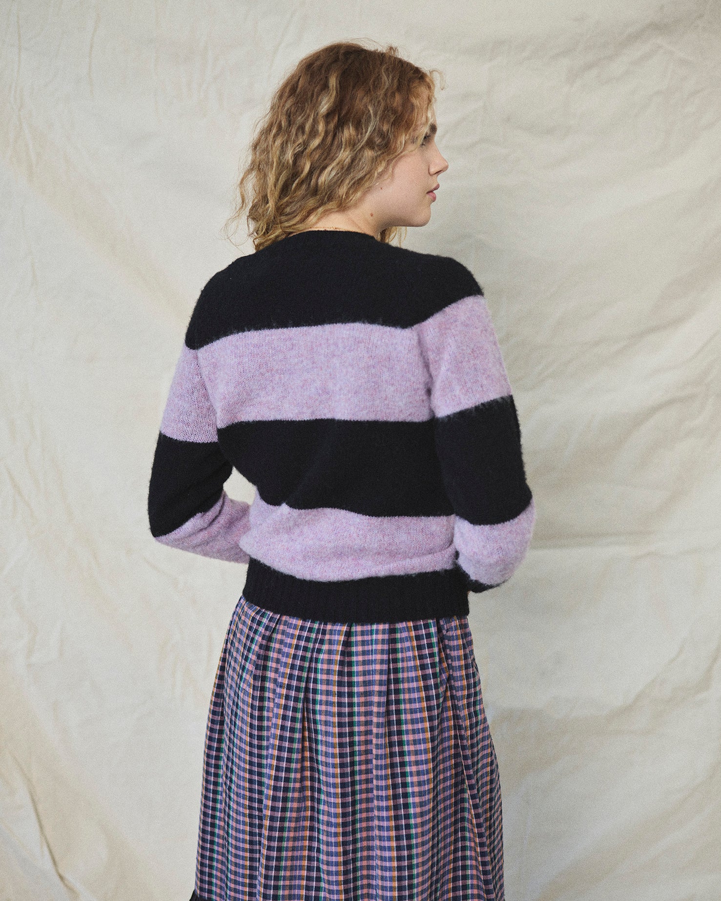 A striped Scottish jumper with horizontal black and lilac blocks, featuring a round neckline and ribbed-knit hemline and trim around neck and wrist.