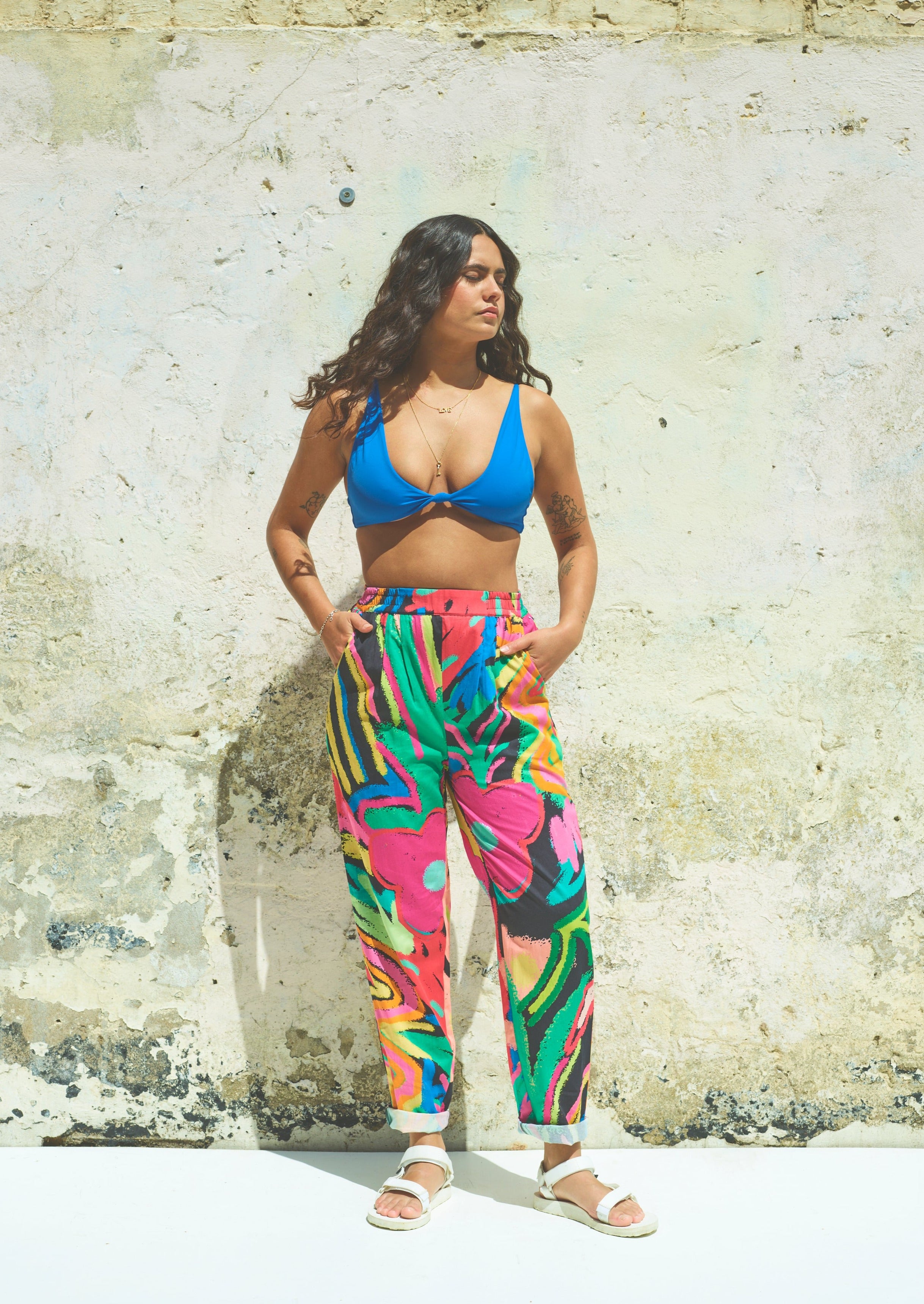 A pair of Miss Pompom Jungle Holiday Trousers with a vibrant hand-drawn tropical print in bright colors.