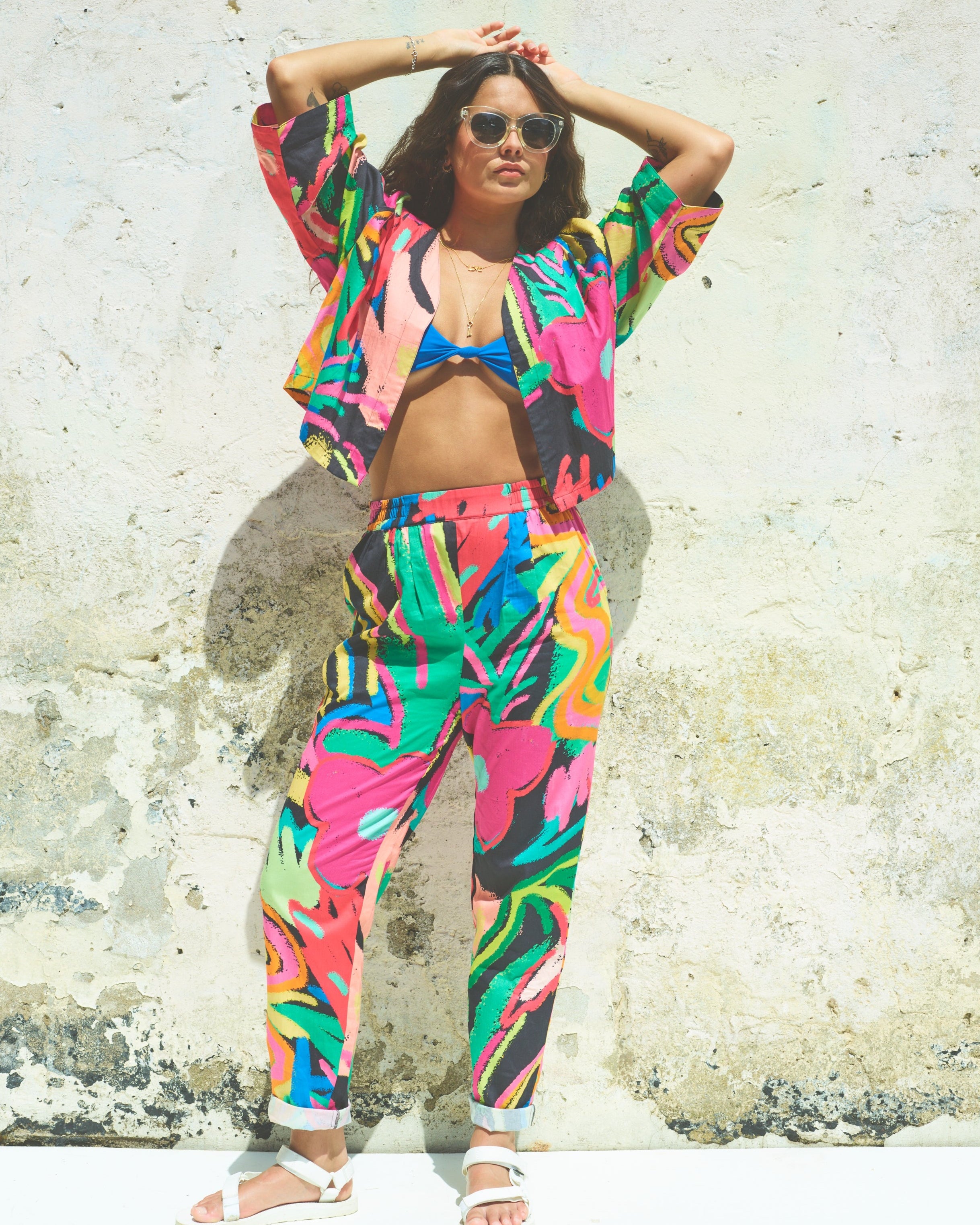 A pair of Miss Pompom Jungle Holiday Trousers with a vibrant hand-drawn tropical print in bright colors.