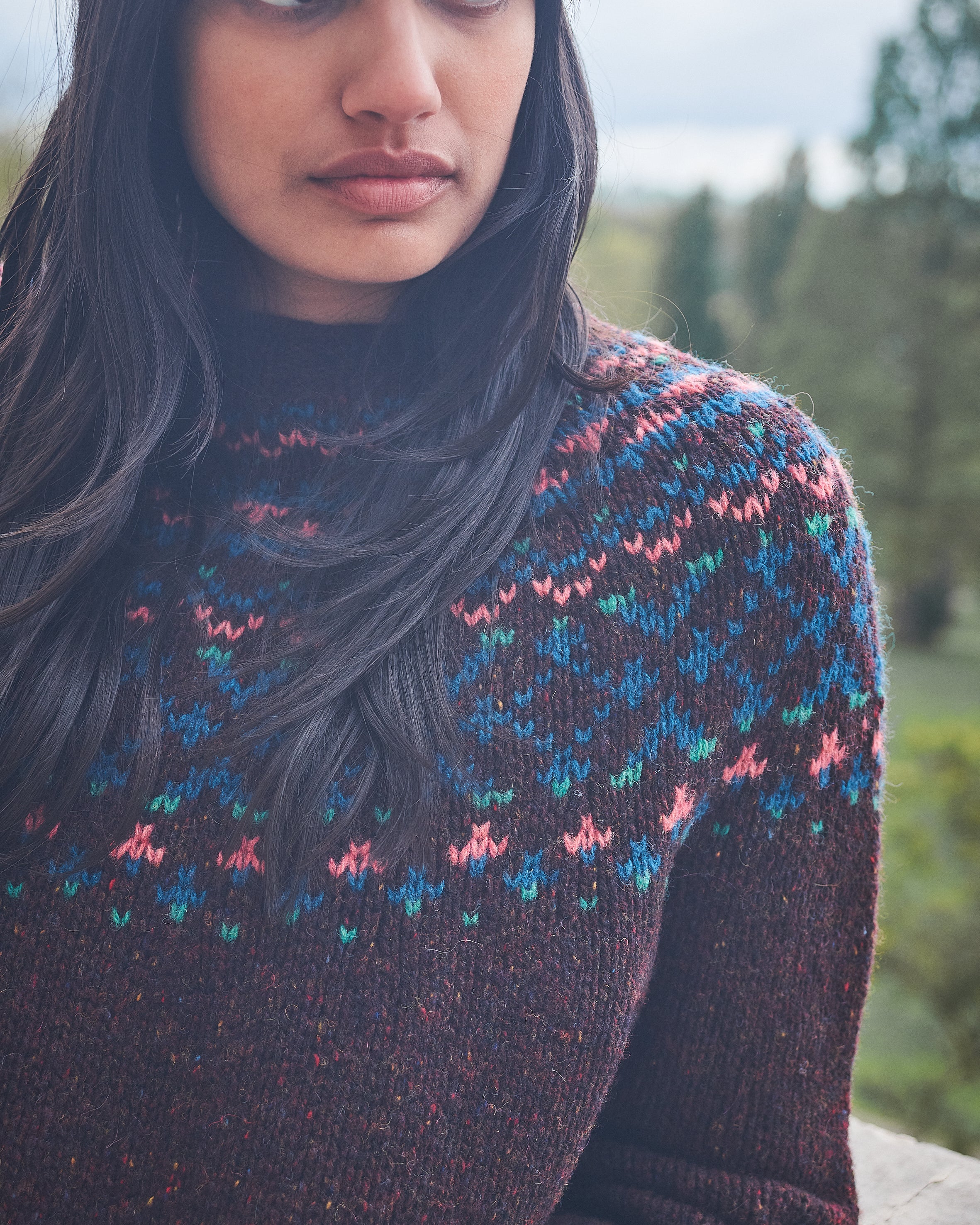Woman wearing a patterned sweater with a blurred natural background