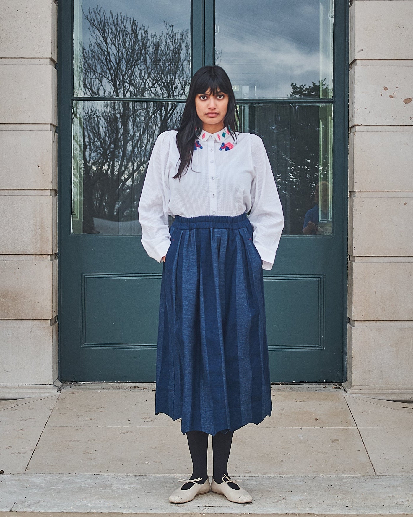 Woman standing in front of a building with columns and large windows