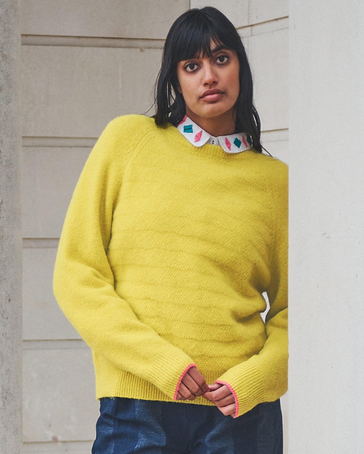 Woman wearing a bright yellow sweater with a neutral background