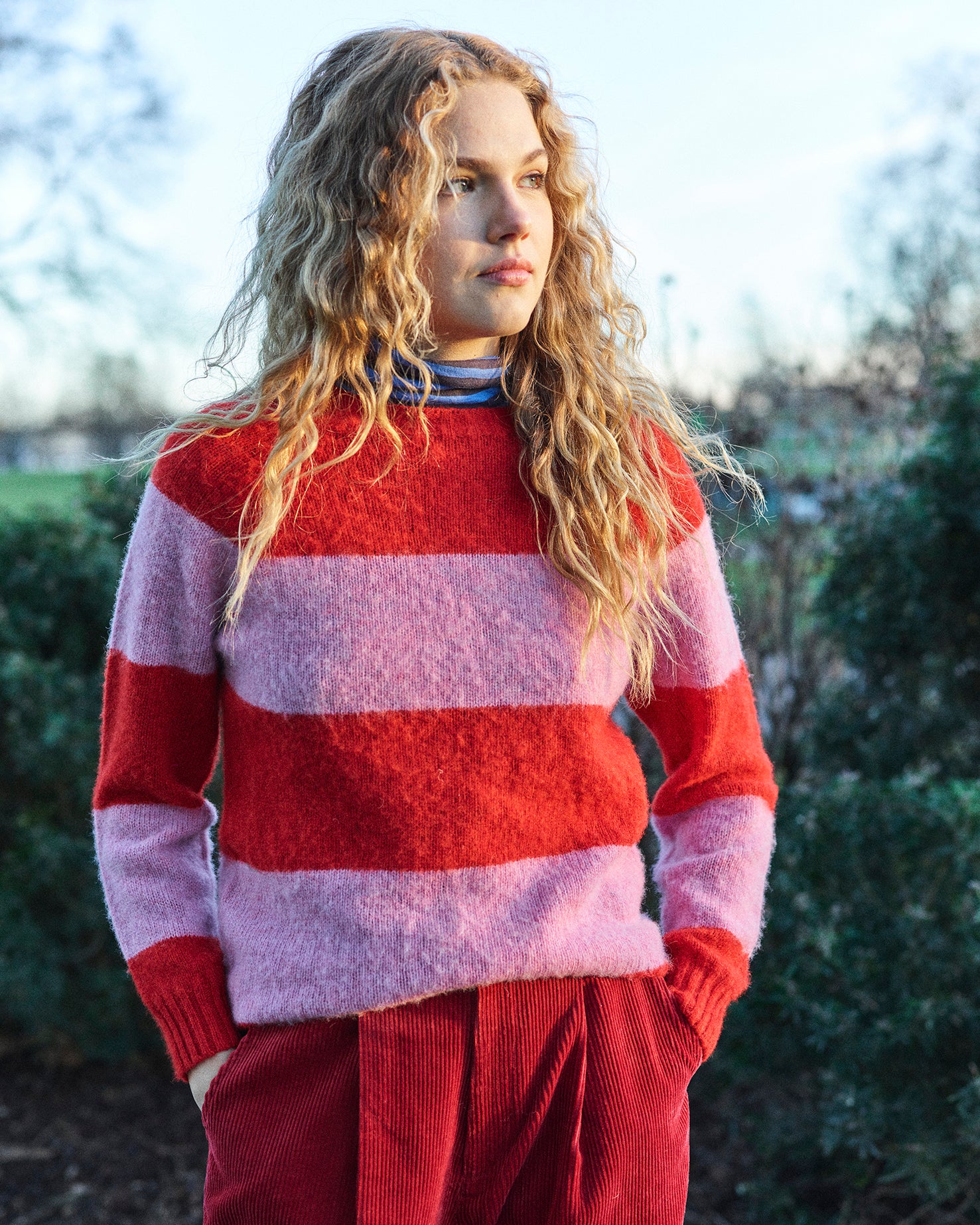 A striped Scottish jumper in pink and red with a round neckline and ribbed-knit hemline and trim around neck and wrist.