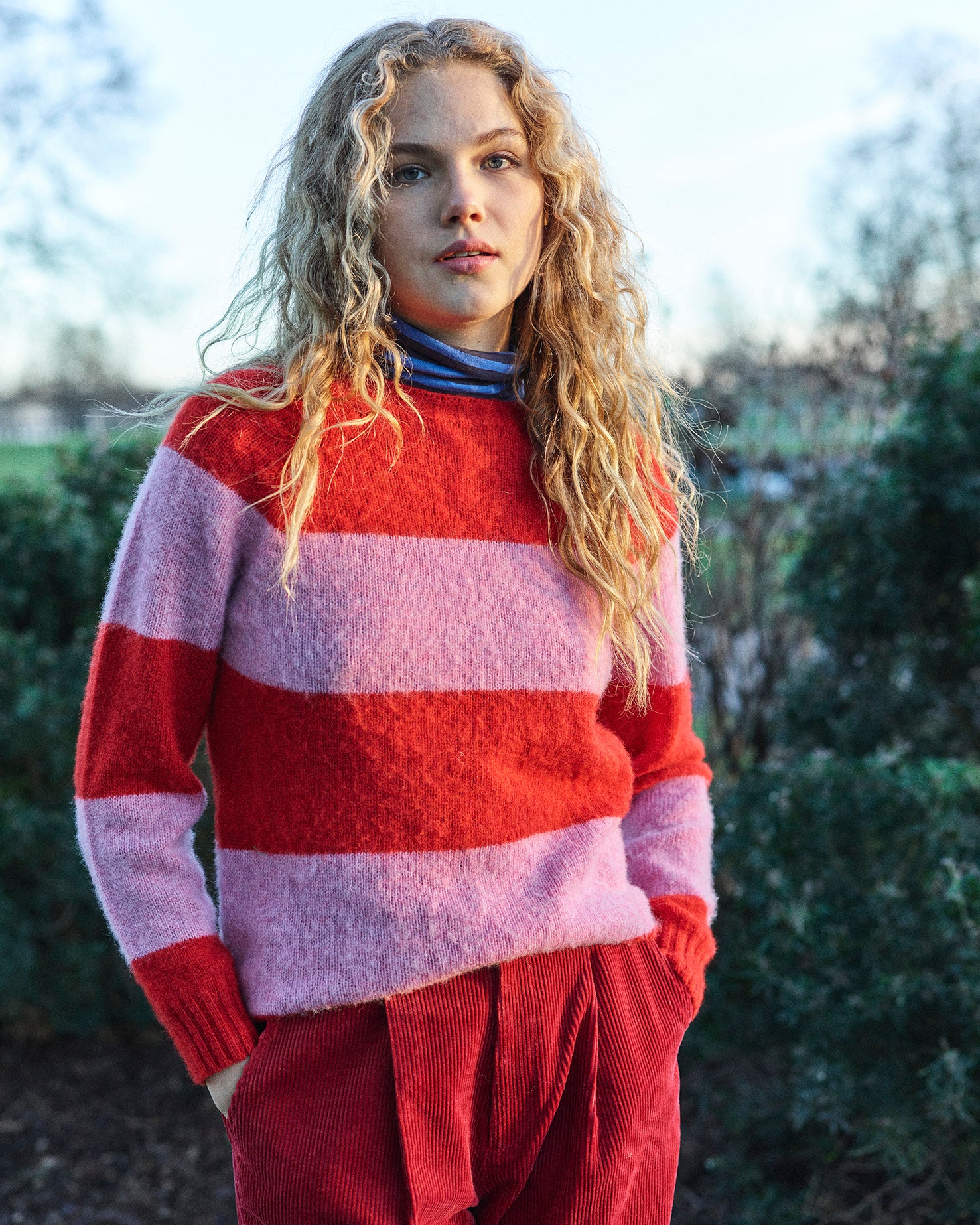 A striped Scottish jumper in pink and red with a round neckline and ribbed-knit hemline and trim around neck and wrist.