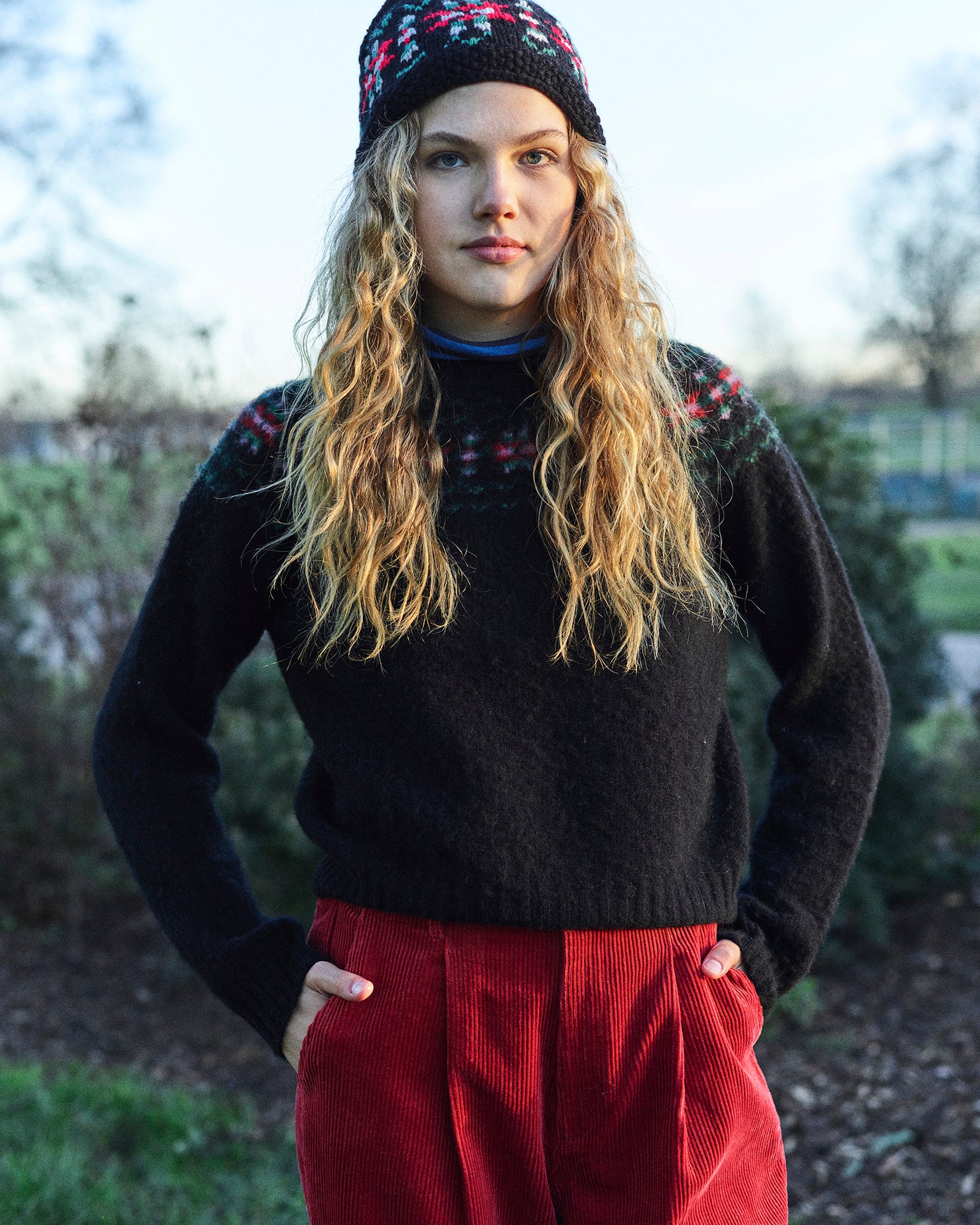 A black sweater with a traditional red, green, and pink fair isle design around the neckline.