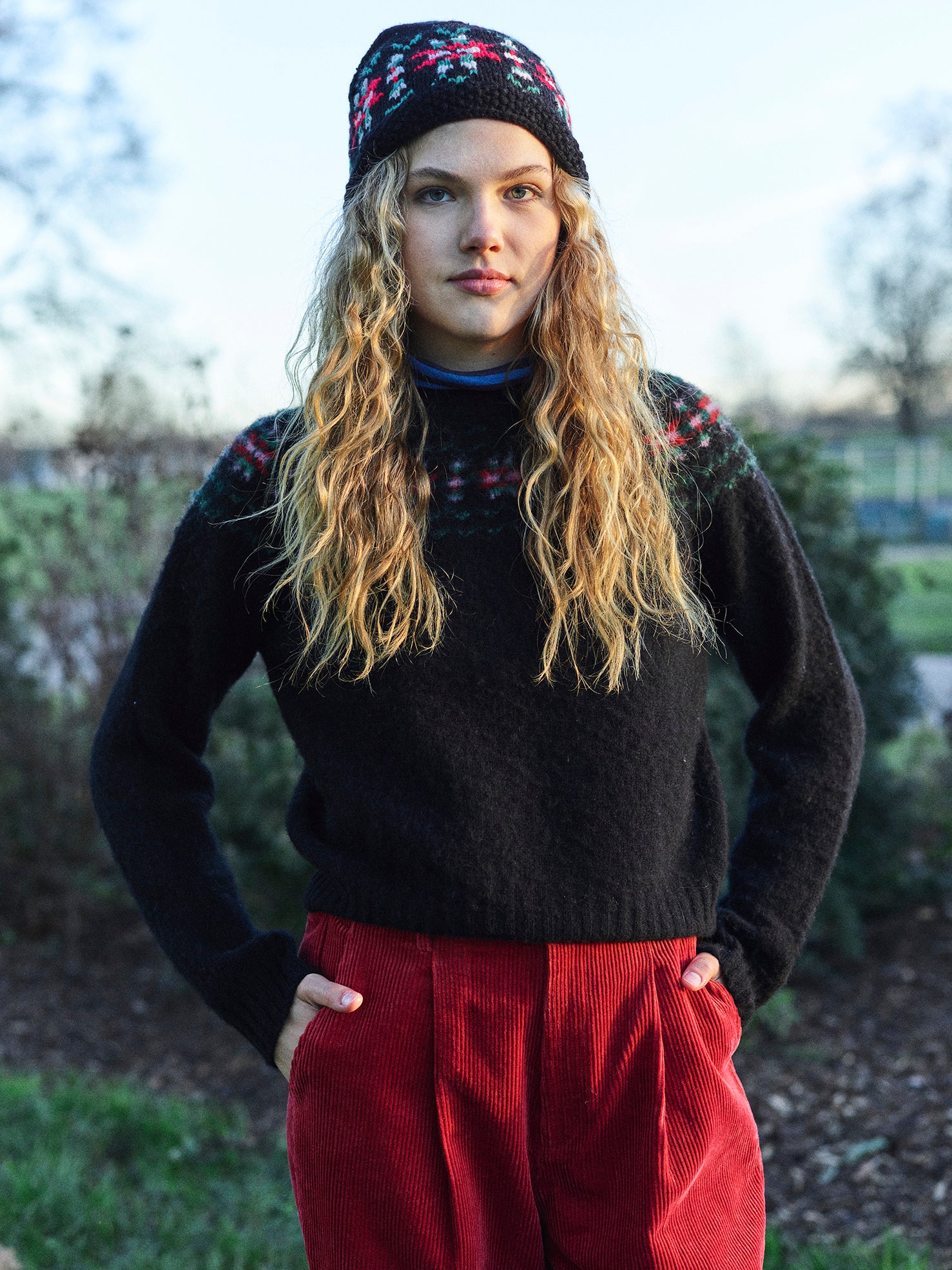 A black sweater with a traditional red, green, and pink fair isle design around the neckline.