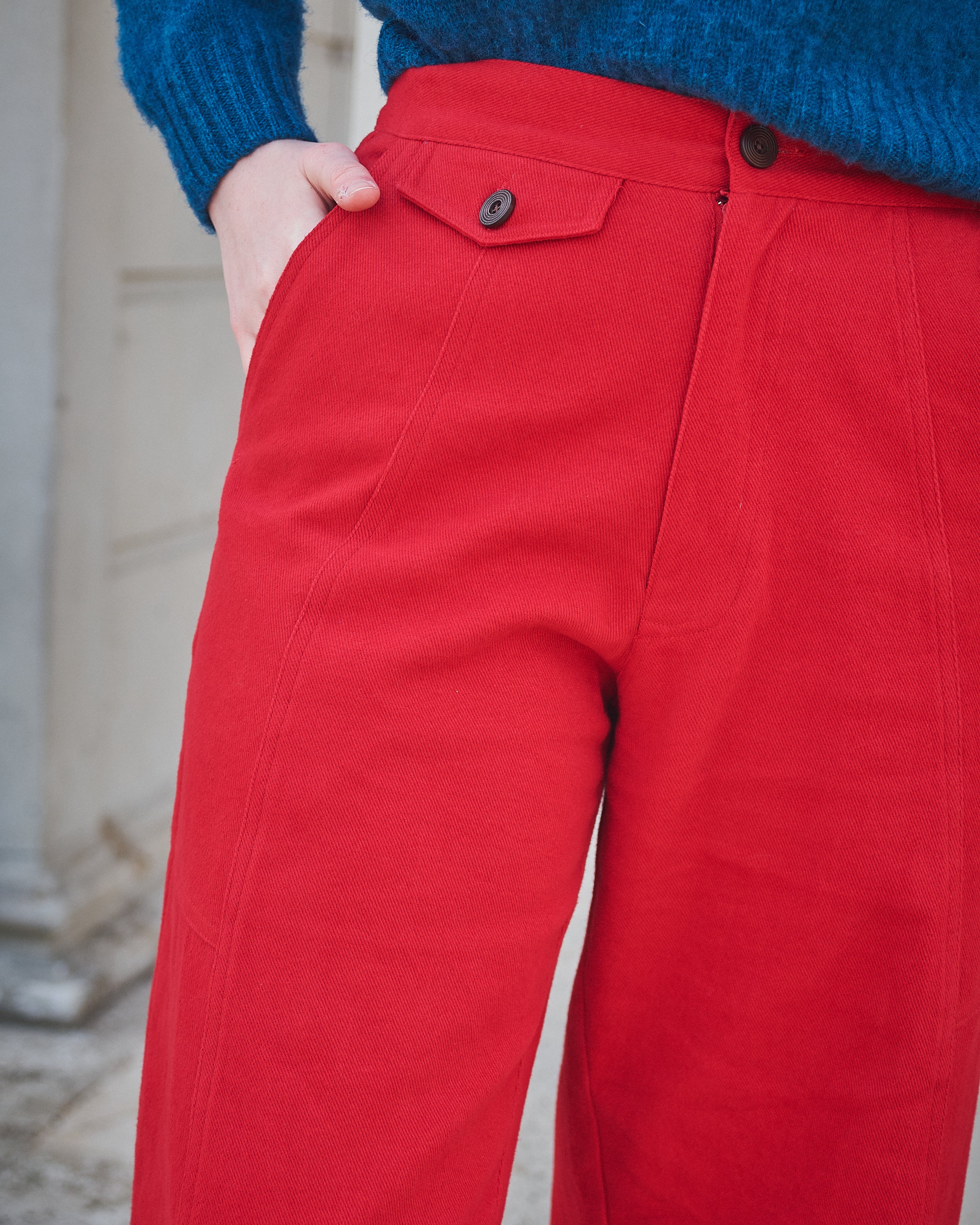 Red pants with a blue sweater worn by a person, blurred background