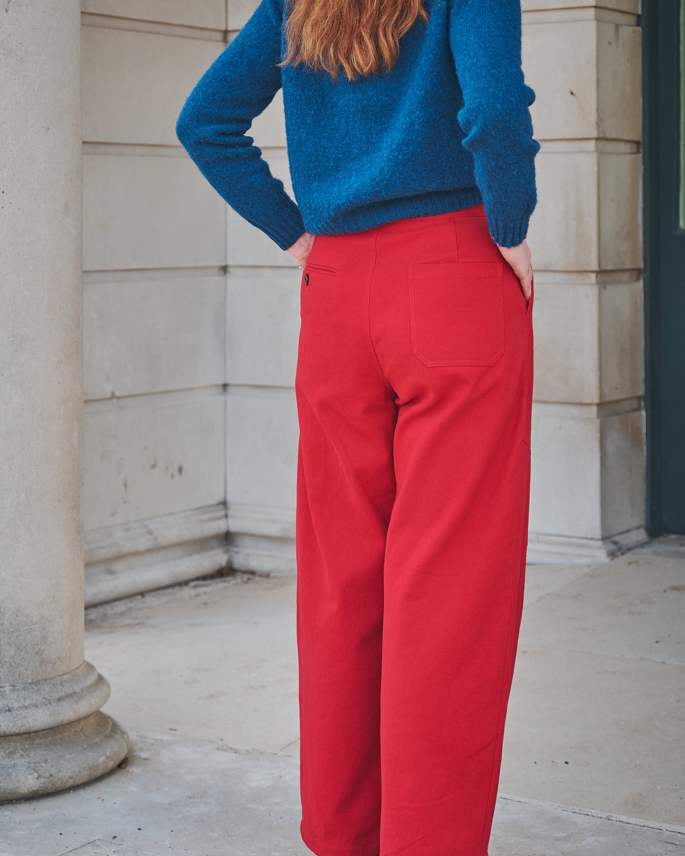 Person wearing a blue sweater and red pants standing outdoors.