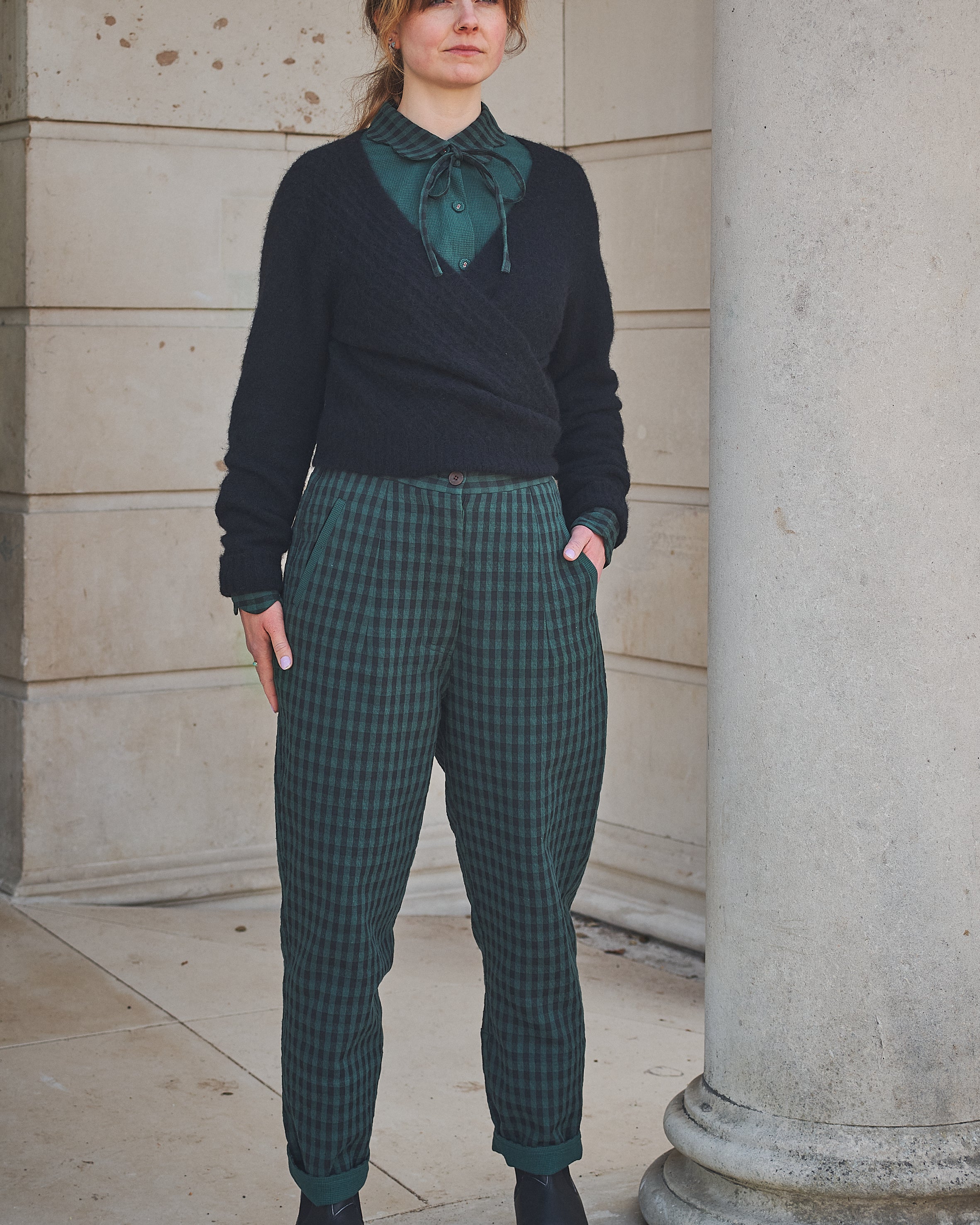 Woman wearing Lowie Green Check Trousers standing against a stone wall.