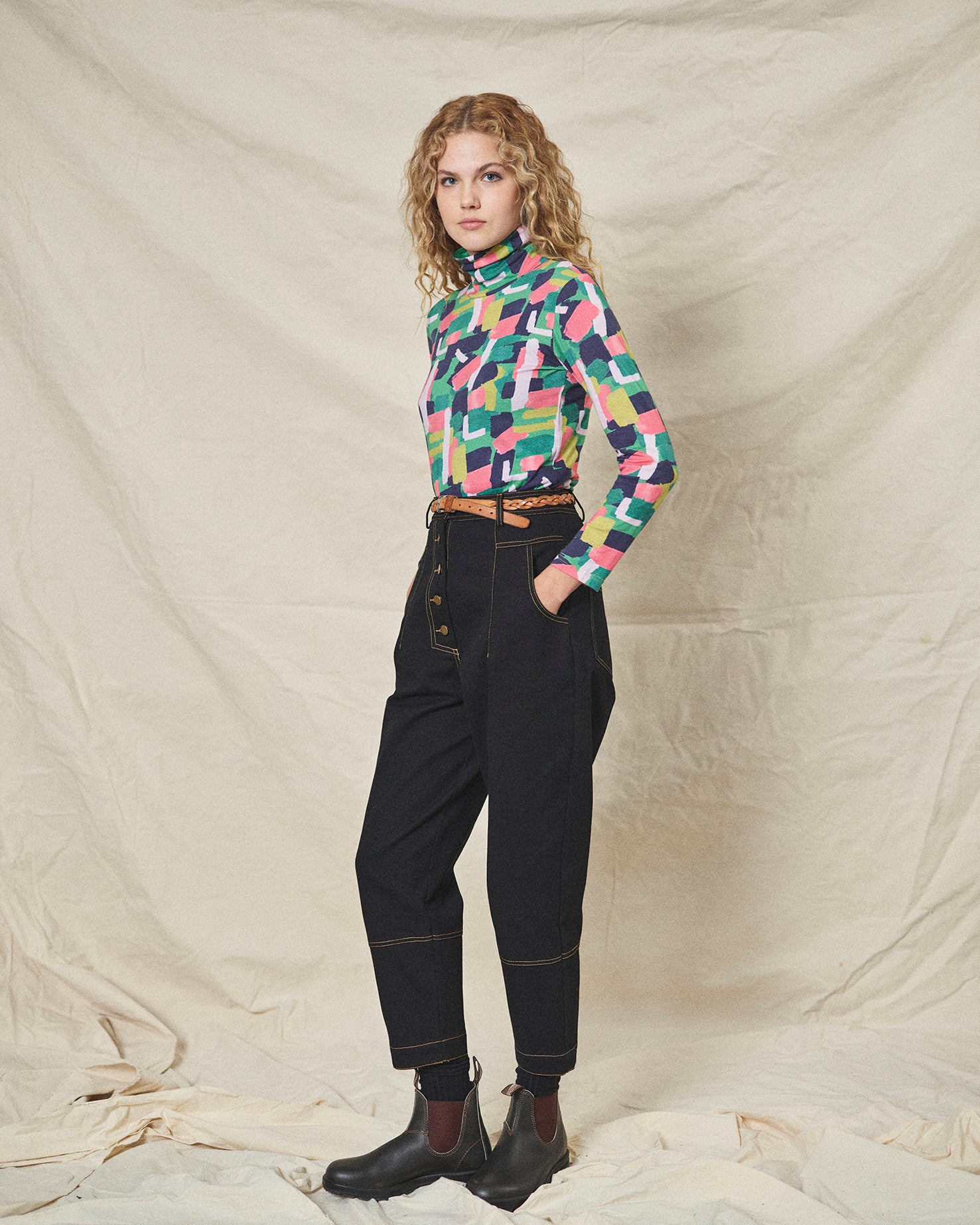 A pair of black cotton drill trousers with a high waist, wide beltband, and 5 button fly front. Features include slanted side pockets and raw stitching.