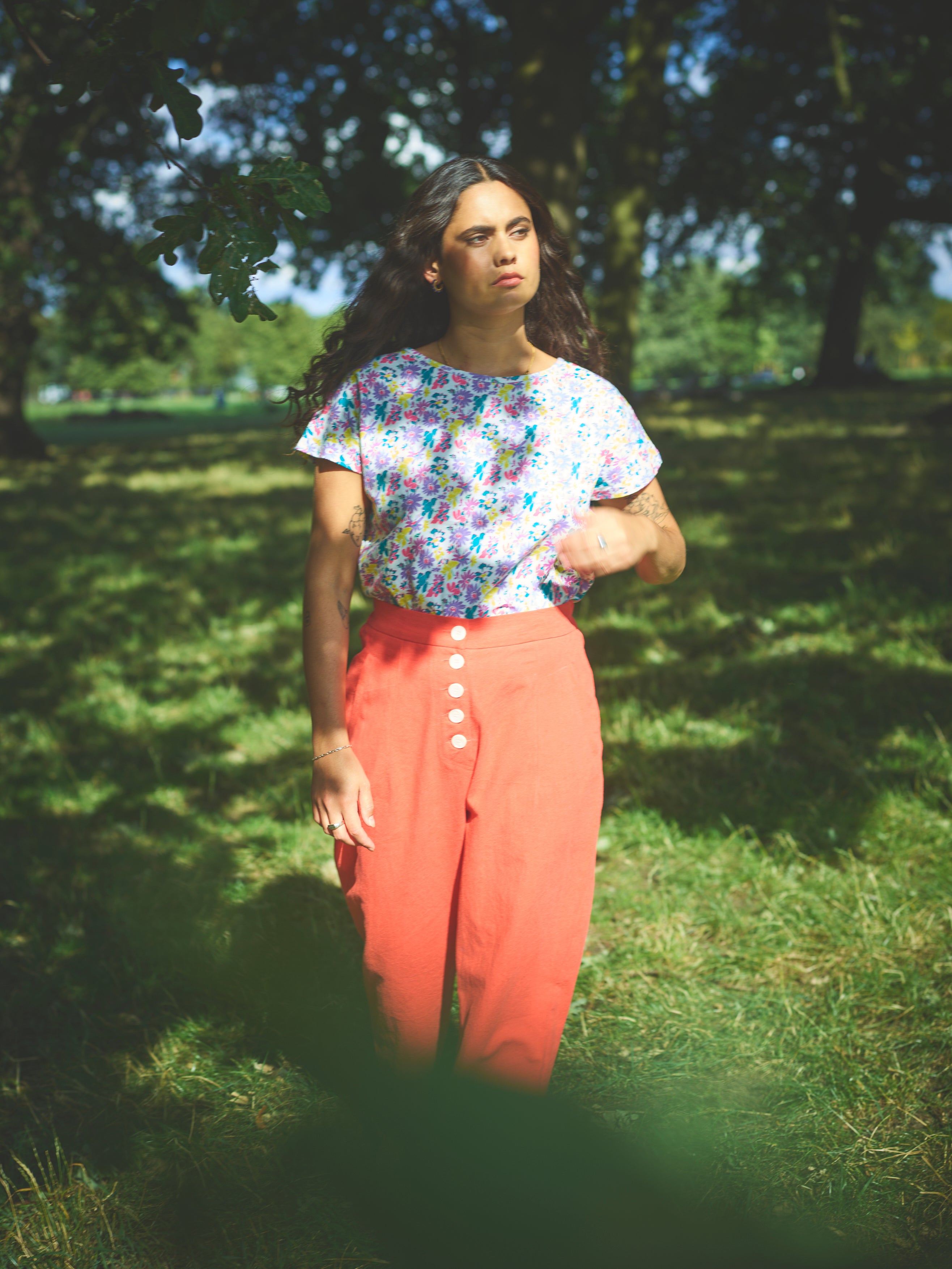 A pair of red cotton linen trousers with side welt pockets and a row of buttons down the front.