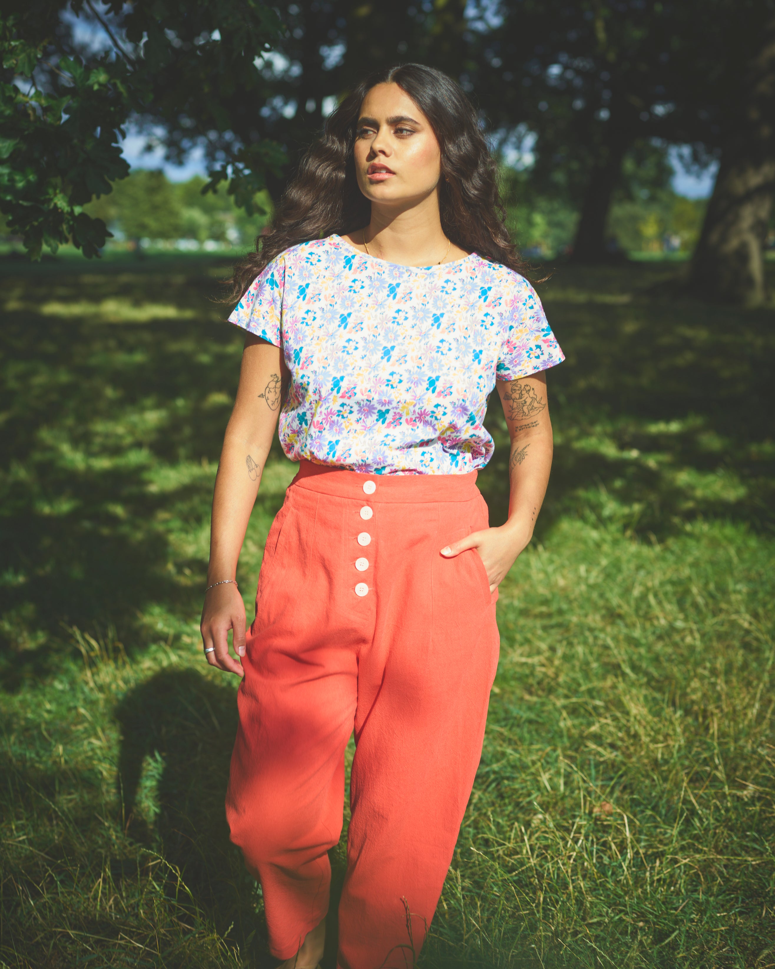 A pair of red cotton linen trousers with side welt pockets and a row of buttons down the front.