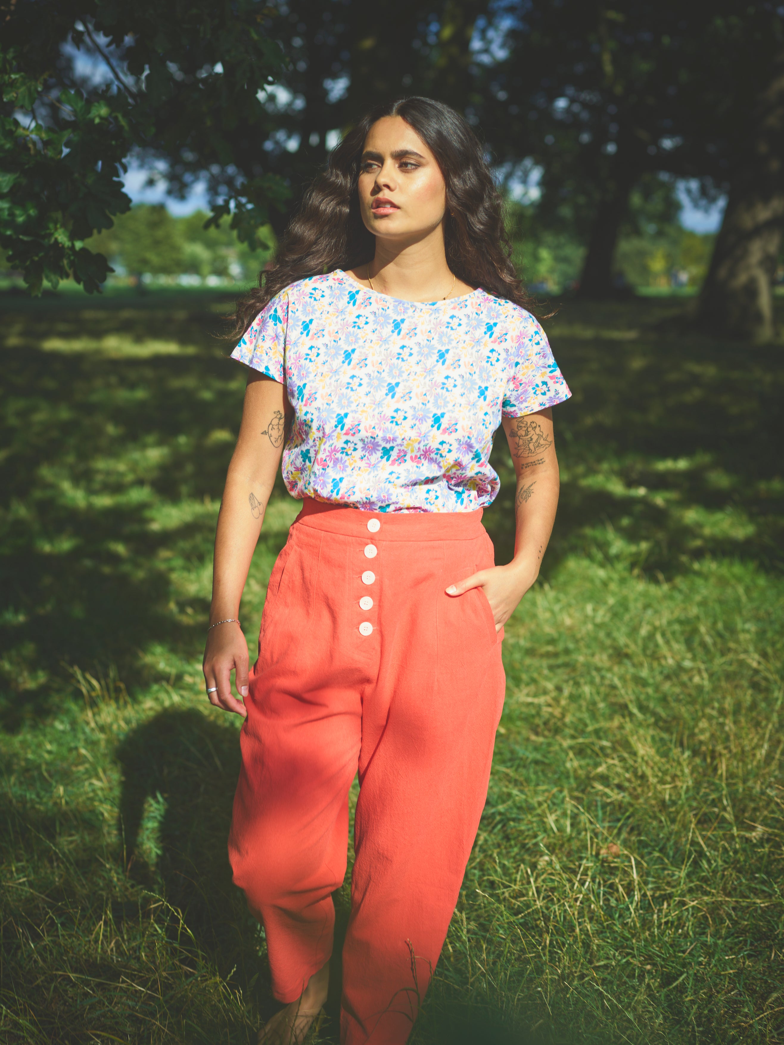 A pair of red cotton linen trousers with side welt pockets and a row of buttons down the front.