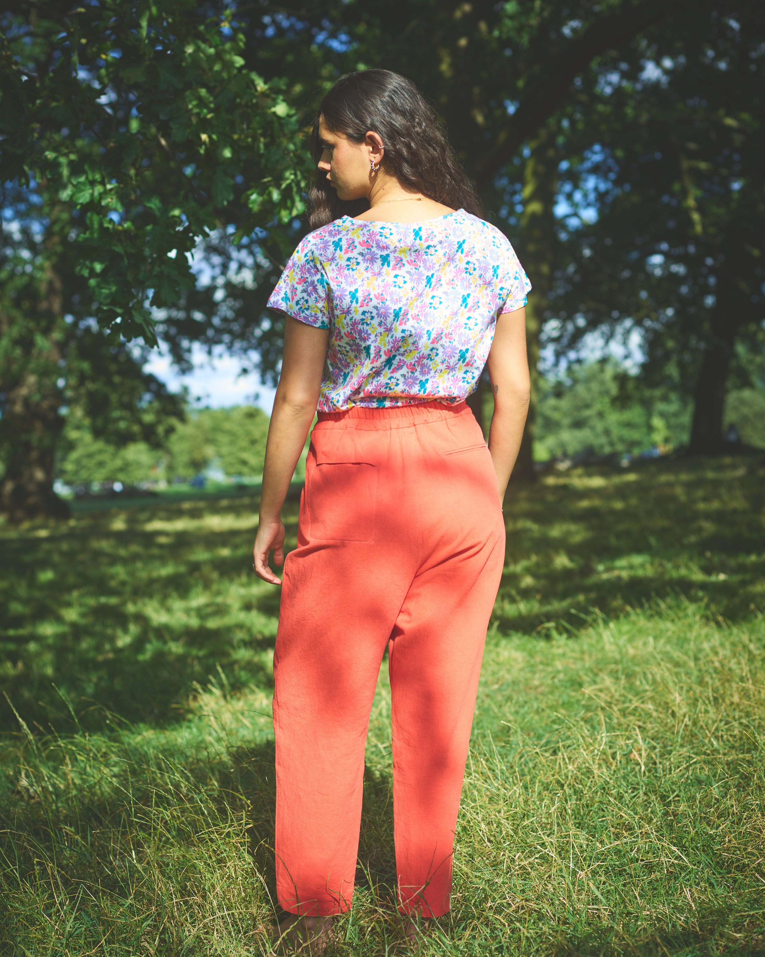 A pair of red cotton linen trousers with side welt pockets and a row of buttons down the front.