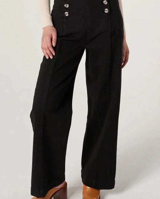 Woman wearing a sheer top and black pants on a white background