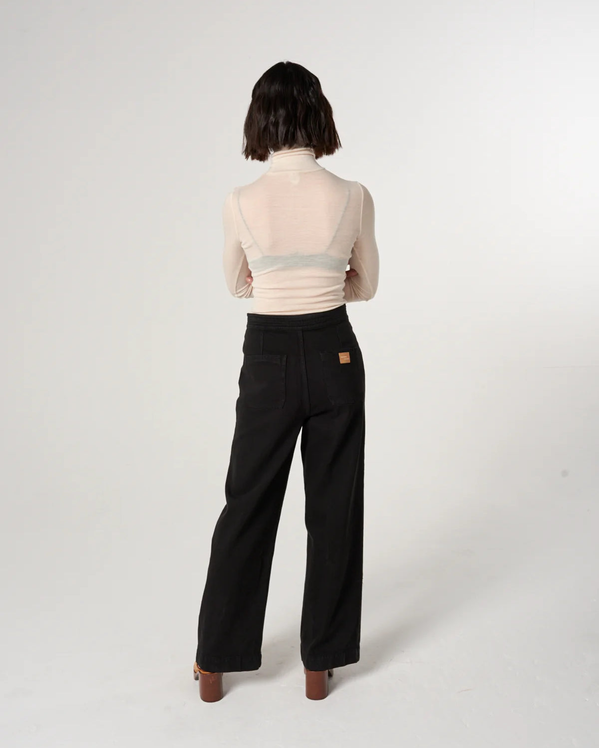 Person wearing a light pink top and black pants on a white background