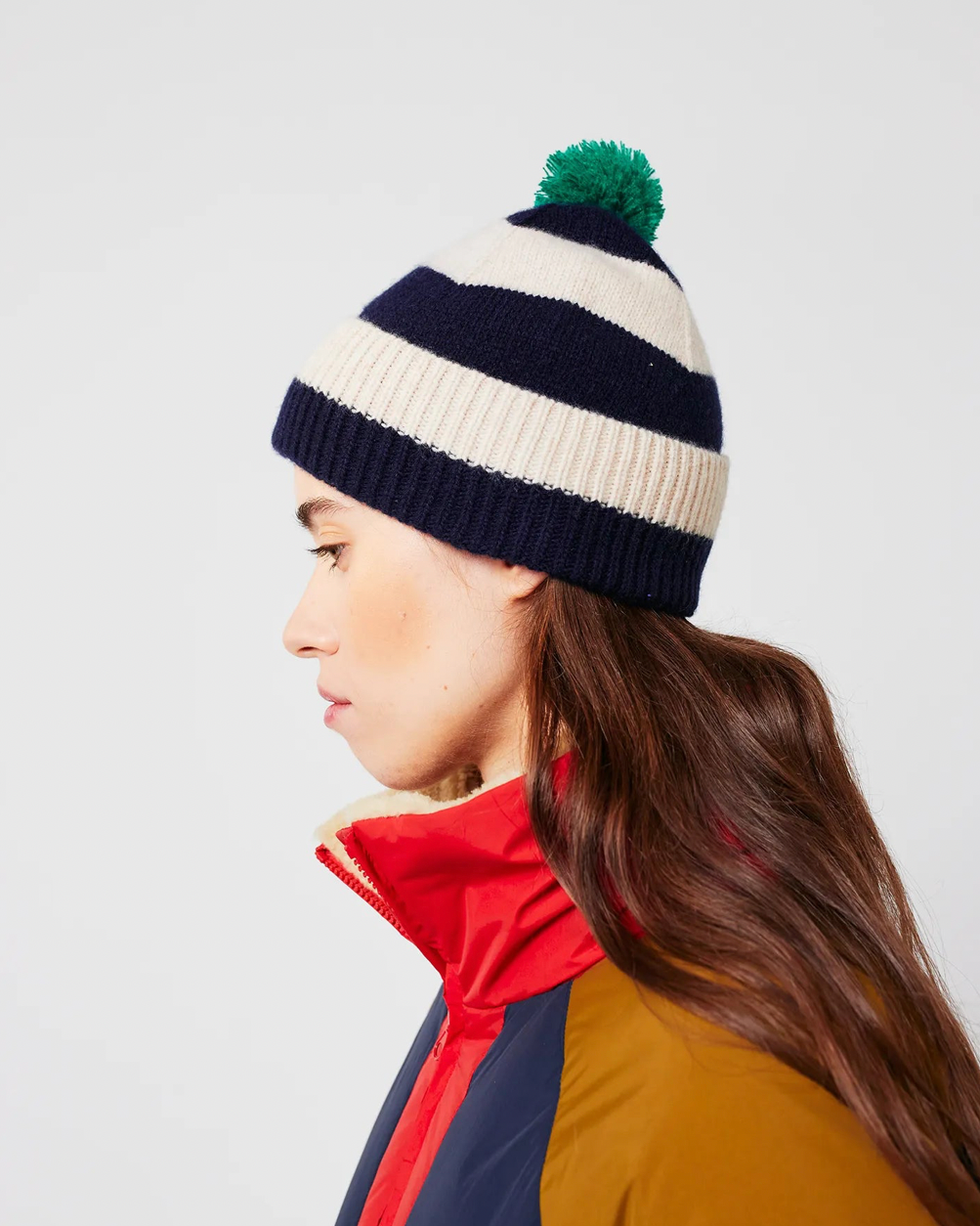 Person wearing a striped beanie with a pom-pom on a white background