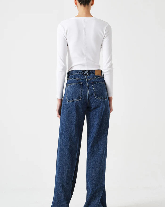 Person wearing blue jeans and a white long-sleeve shirt on a white background