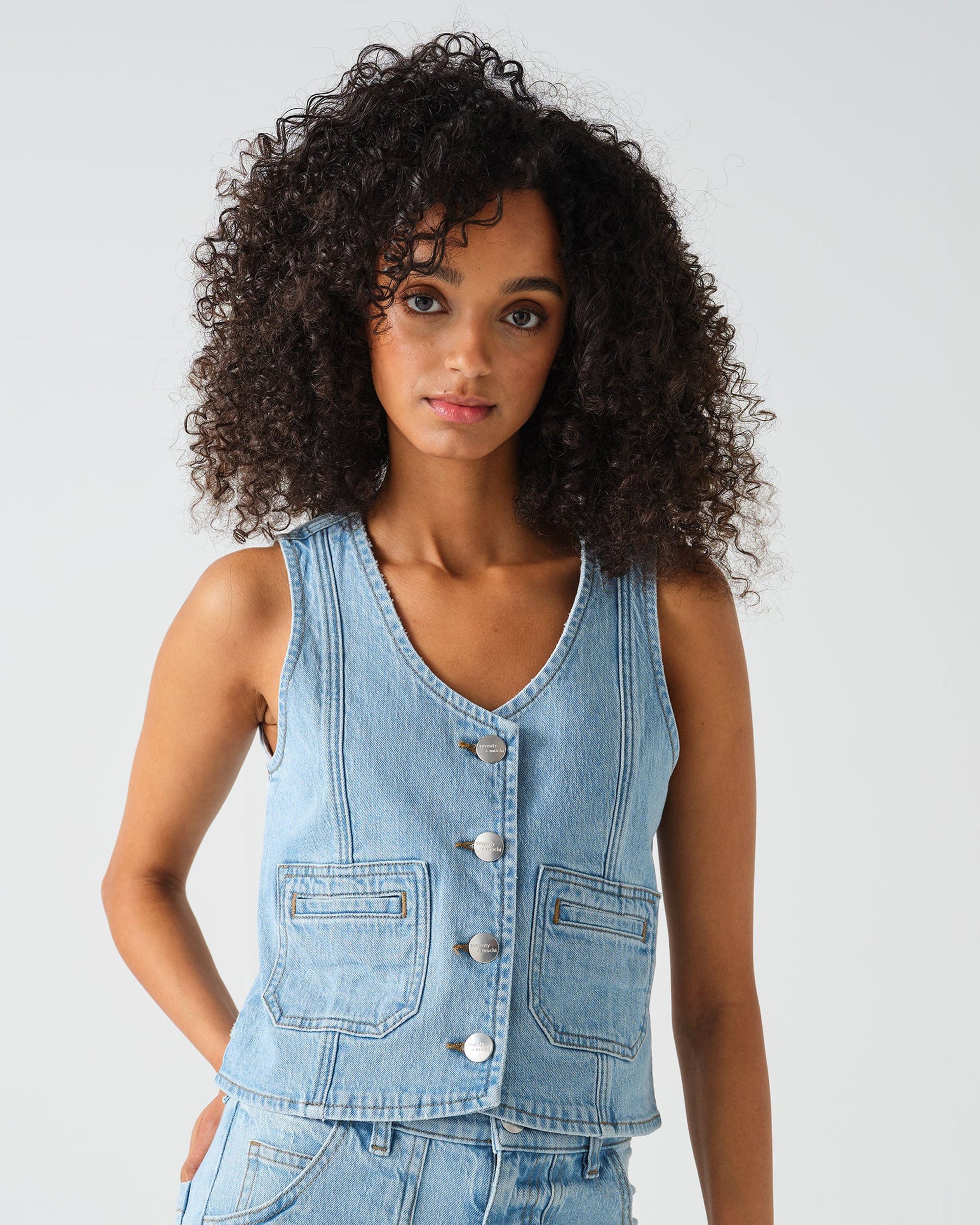 Woman wearing a denim vest against a plain background