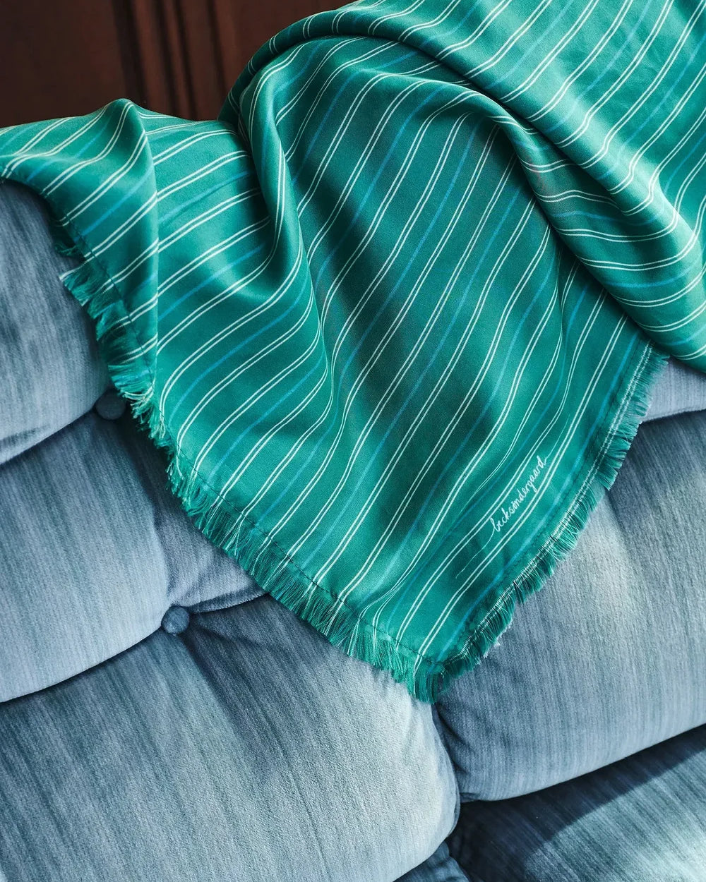 Green striped blanket draped over a gray sofa