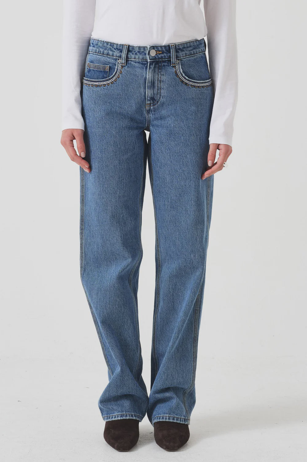 Person wearing blue jeans and a white shirt on a plain background