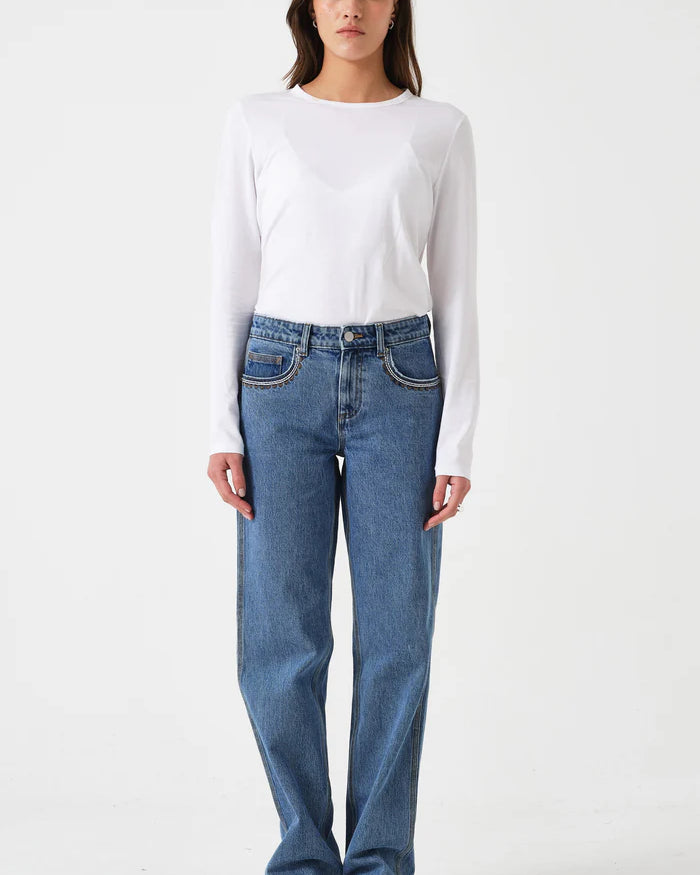 Person wearing a white long-sleeve shirt and blue jeans on a white background