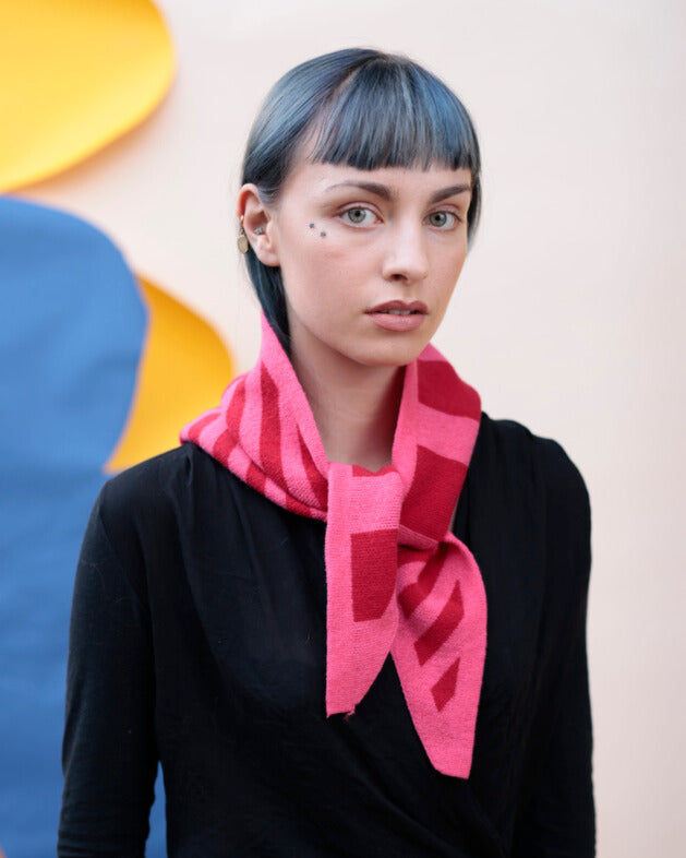 Person wearing a pink scarf with a colorful abstract background