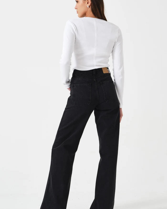 Person wearing a white long-sleeve top and black pants on a white background