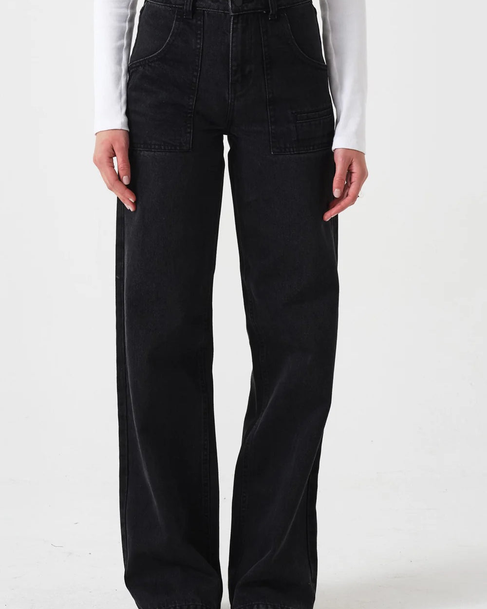 Person wearing black flared jeans and a white long-sleeve shirt on a white background