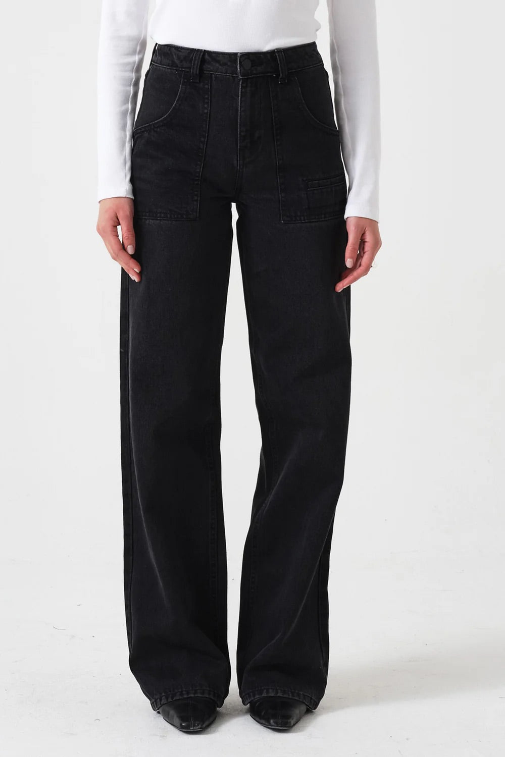 Person wearing black flared jeans and a white long-sleeve shirt on a white background