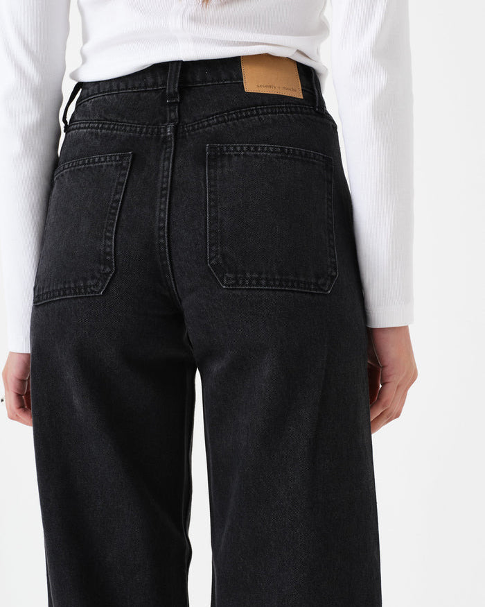 Person wearing black jeans with a white shirt on a plain background