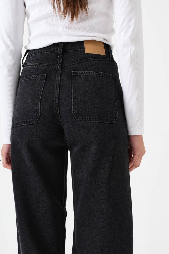 Person wearing black jeans with a white shirt on a plain background