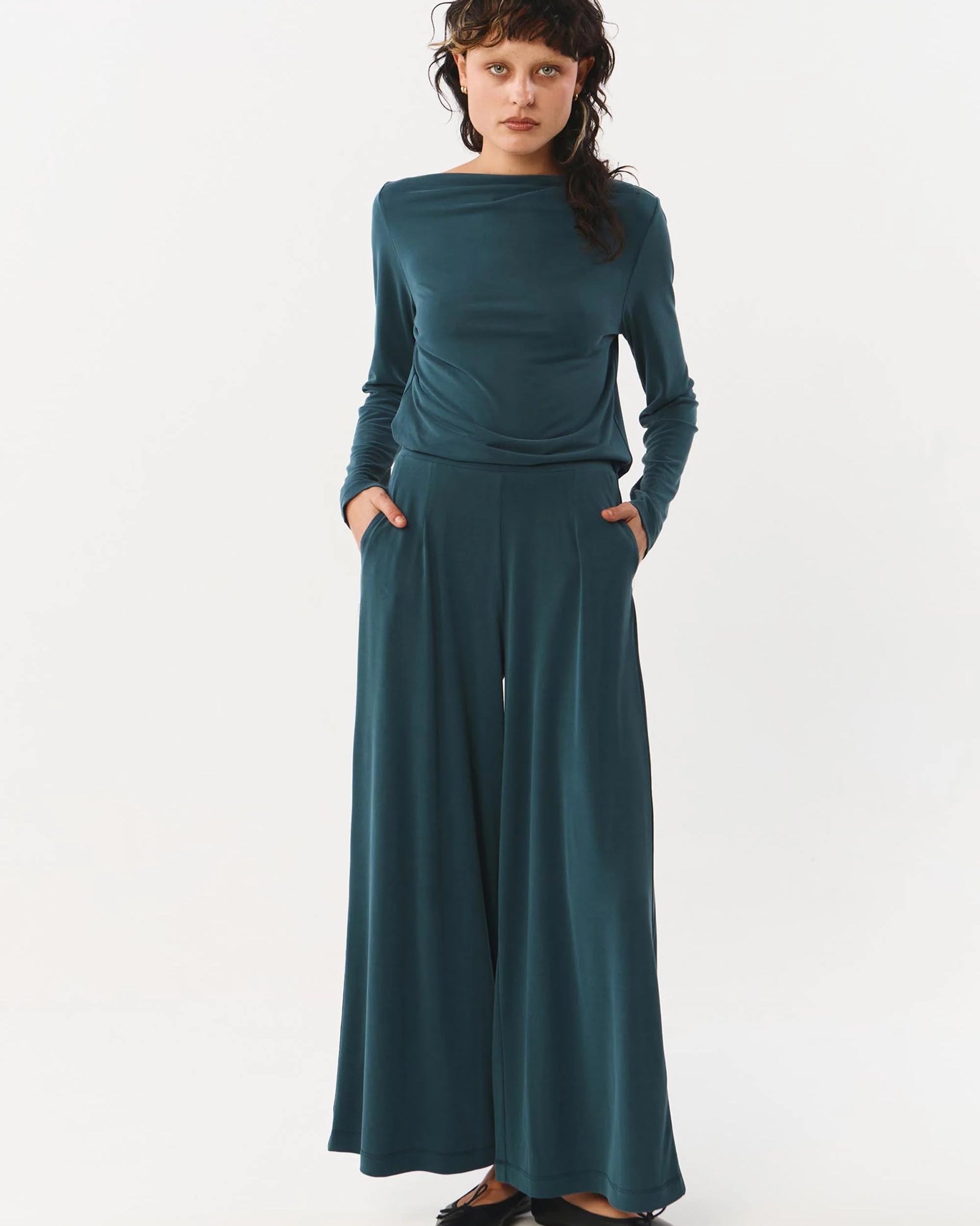 Woman wearing a teal outfit on a white background