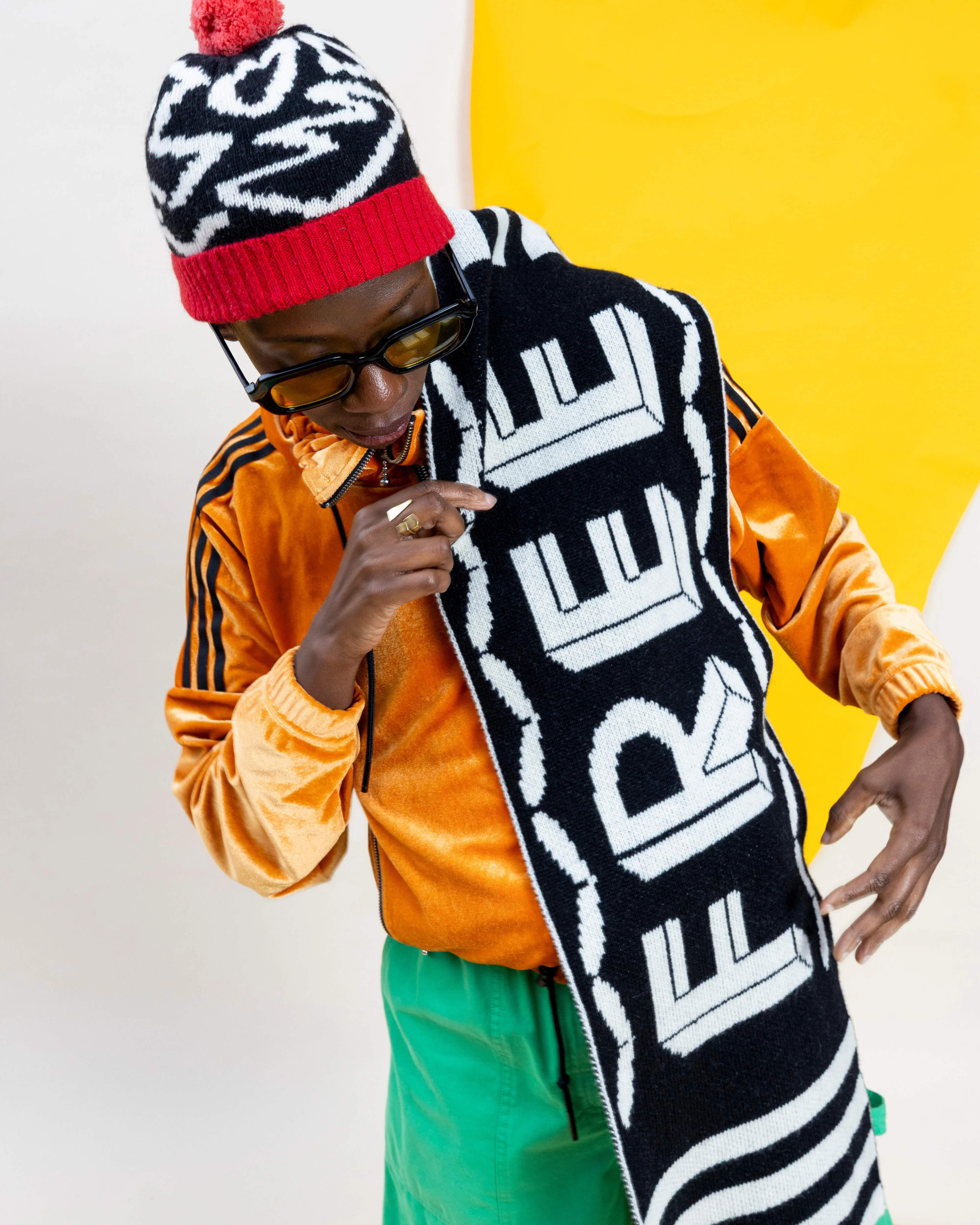 Person wearing a colorful outfit with a scarf that says 'FREE' against a yellow and white background
