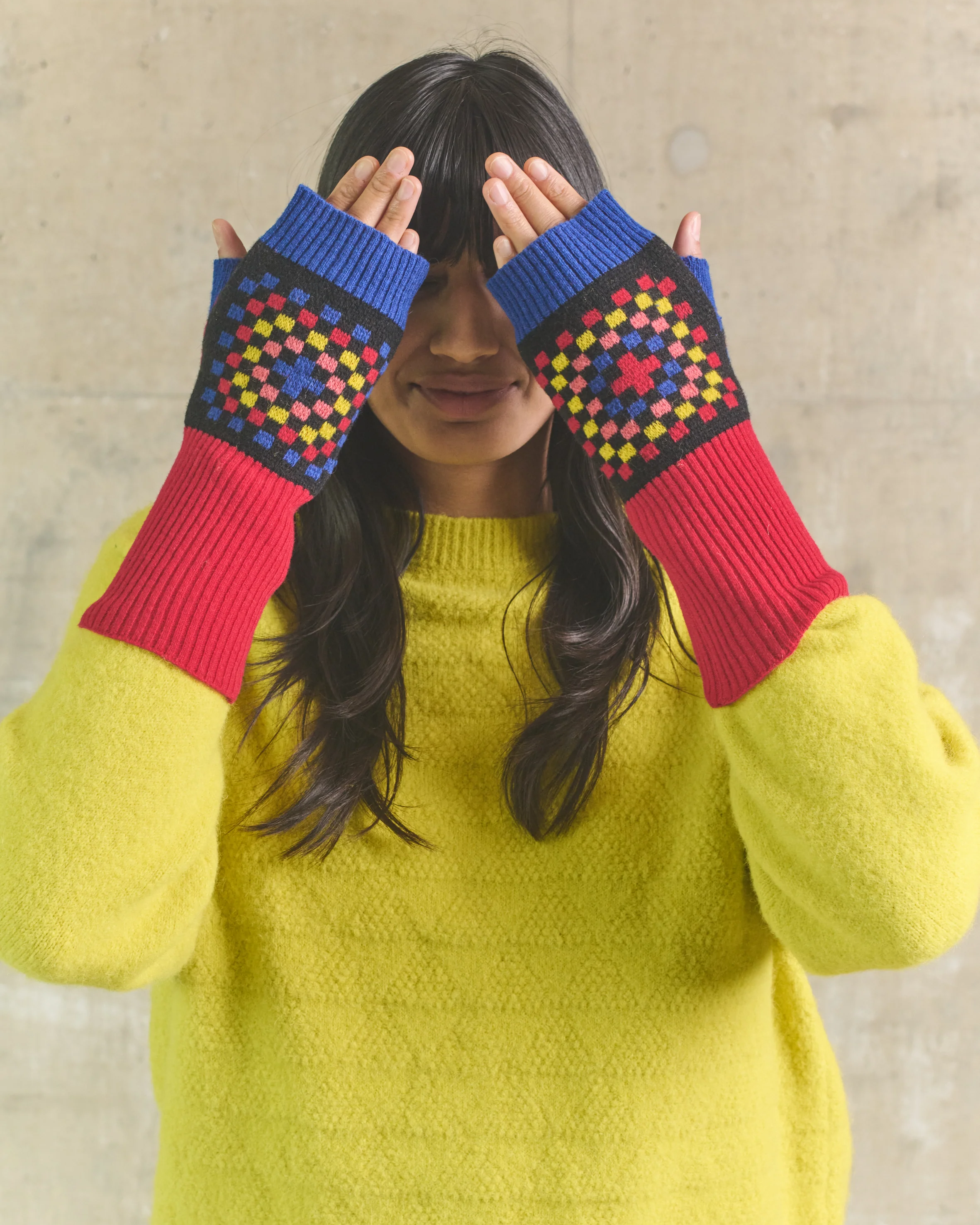 Person wearing colorful fingerless gloves with a geometric pattern against a plain background