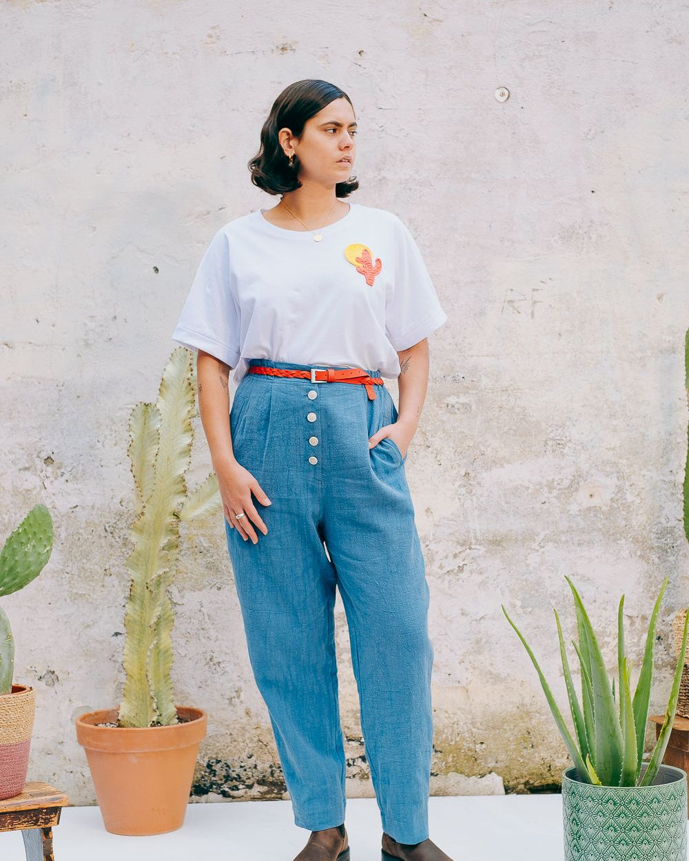 Washed blue cotton linen trousers with side welt pockets and elasticated waist at the back, featuring five corozo buttons down the front.
