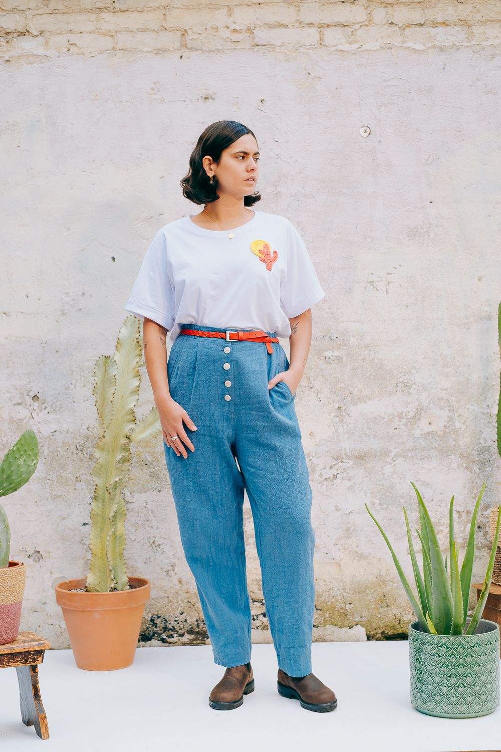 Washed blue cotton linen trousers with side welt pockets and elasticated waist at the back, featuring five corozo buttons down the front.