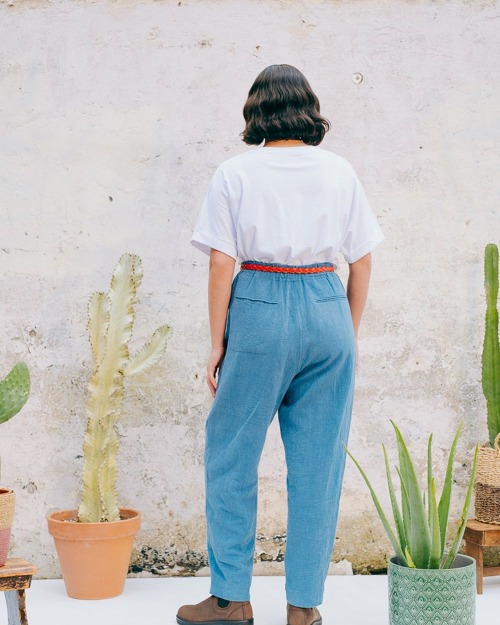 Washed blue cotton linen trousers with side welt pockets and elasticated waist at the back, featuring five corozo buttons down the front.