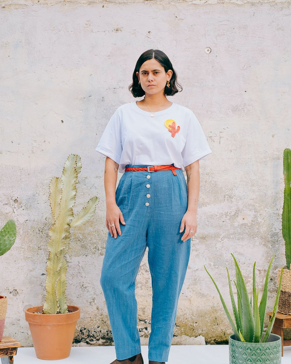 Washed blue cotton linen trousers with side welt pockets and elasticated waist at the back, featuring five corozo buttons down the front.