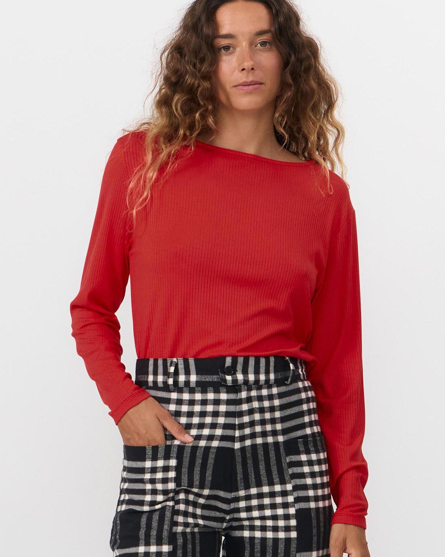 Woman wearing a red top and checkered pants on a white background