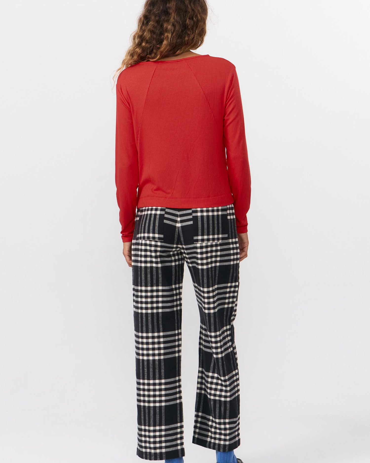 Person wearing a red top and checkered pants on a white background