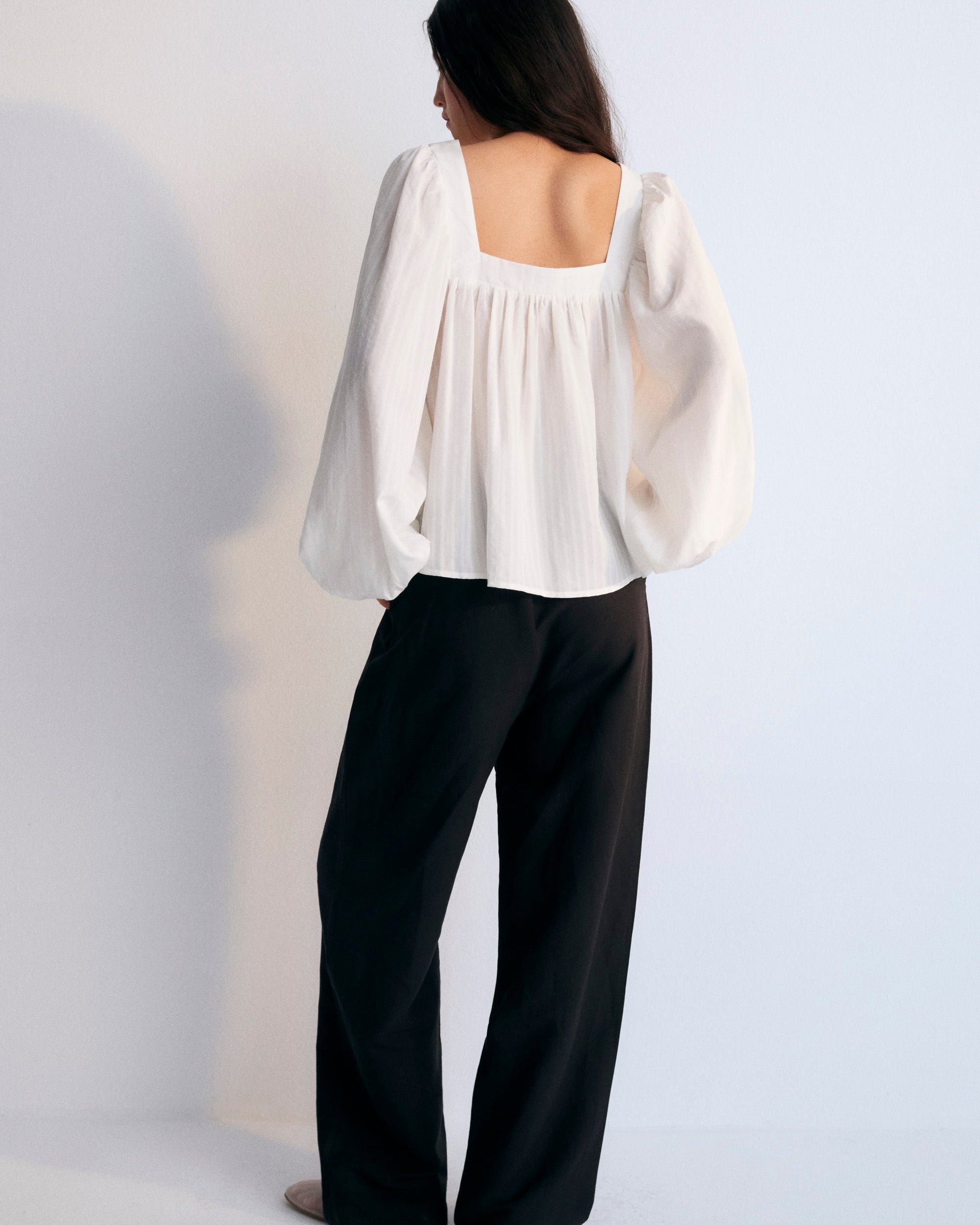 A white Tencel blouse with a square neckline, long sleeves, and elastic cuffs on a plain background.