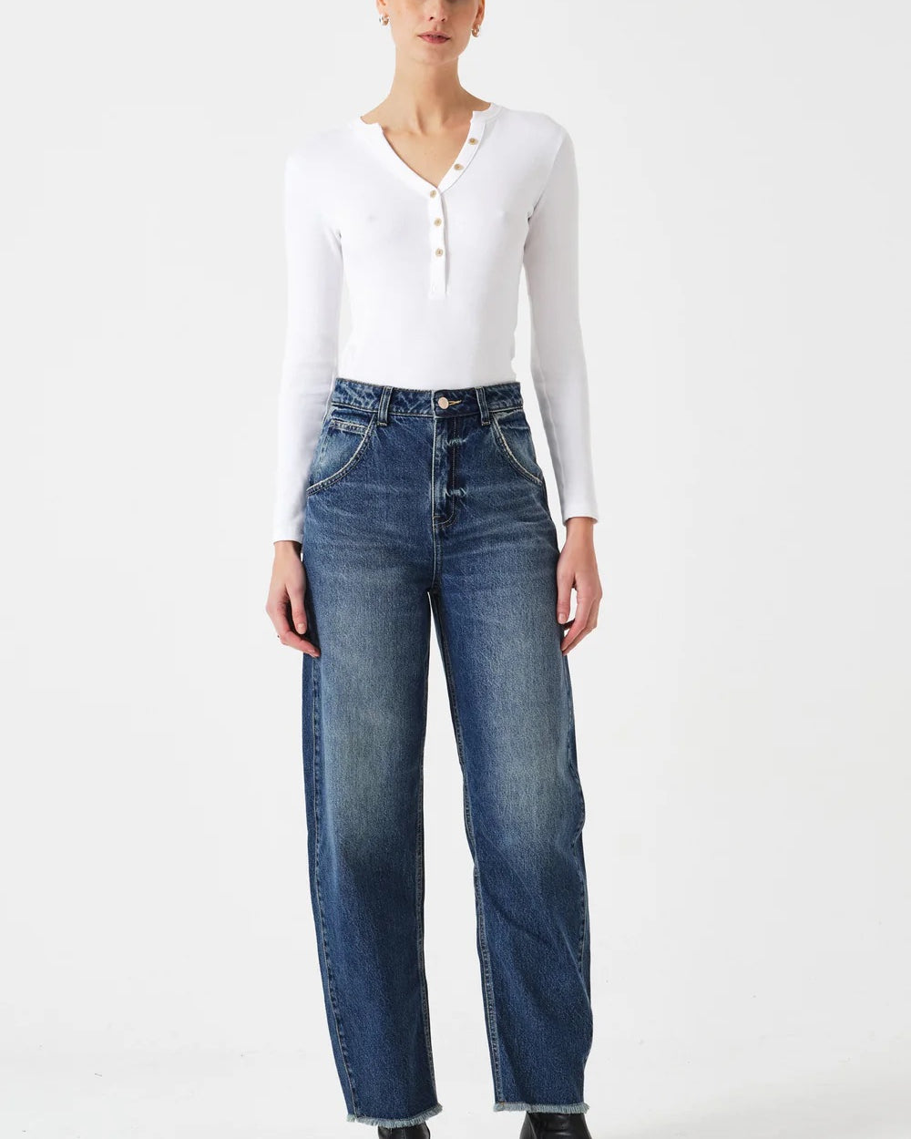 Woman wearing a white long-sleeve top and blue jeans on a white background