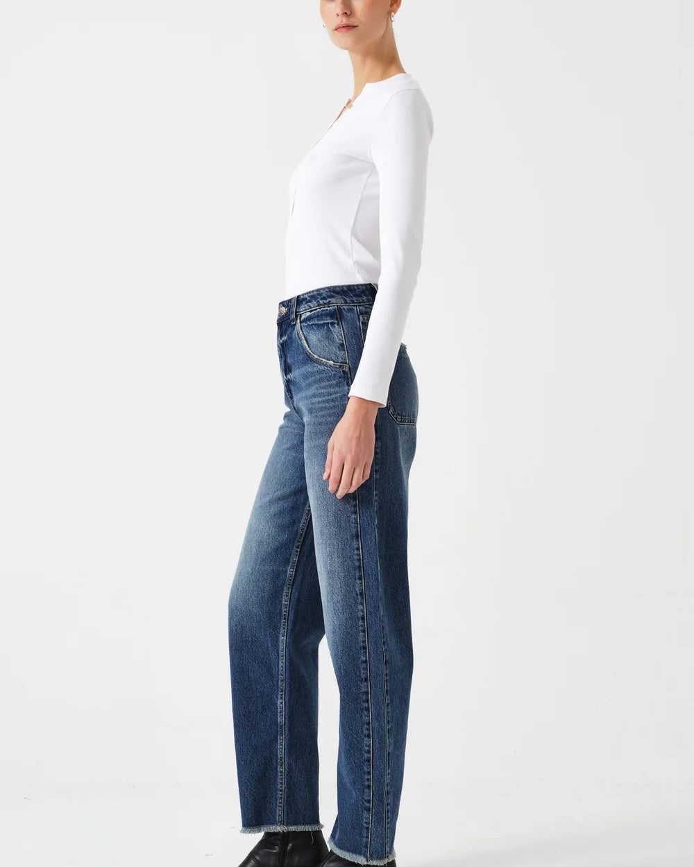 Person wearing a white top and blue jeans on a white background