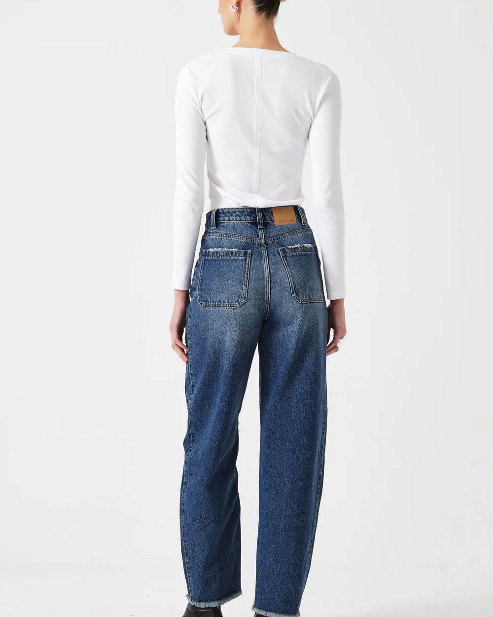 Person wearing blue jeans and a white long-sleeve shirt on a white background